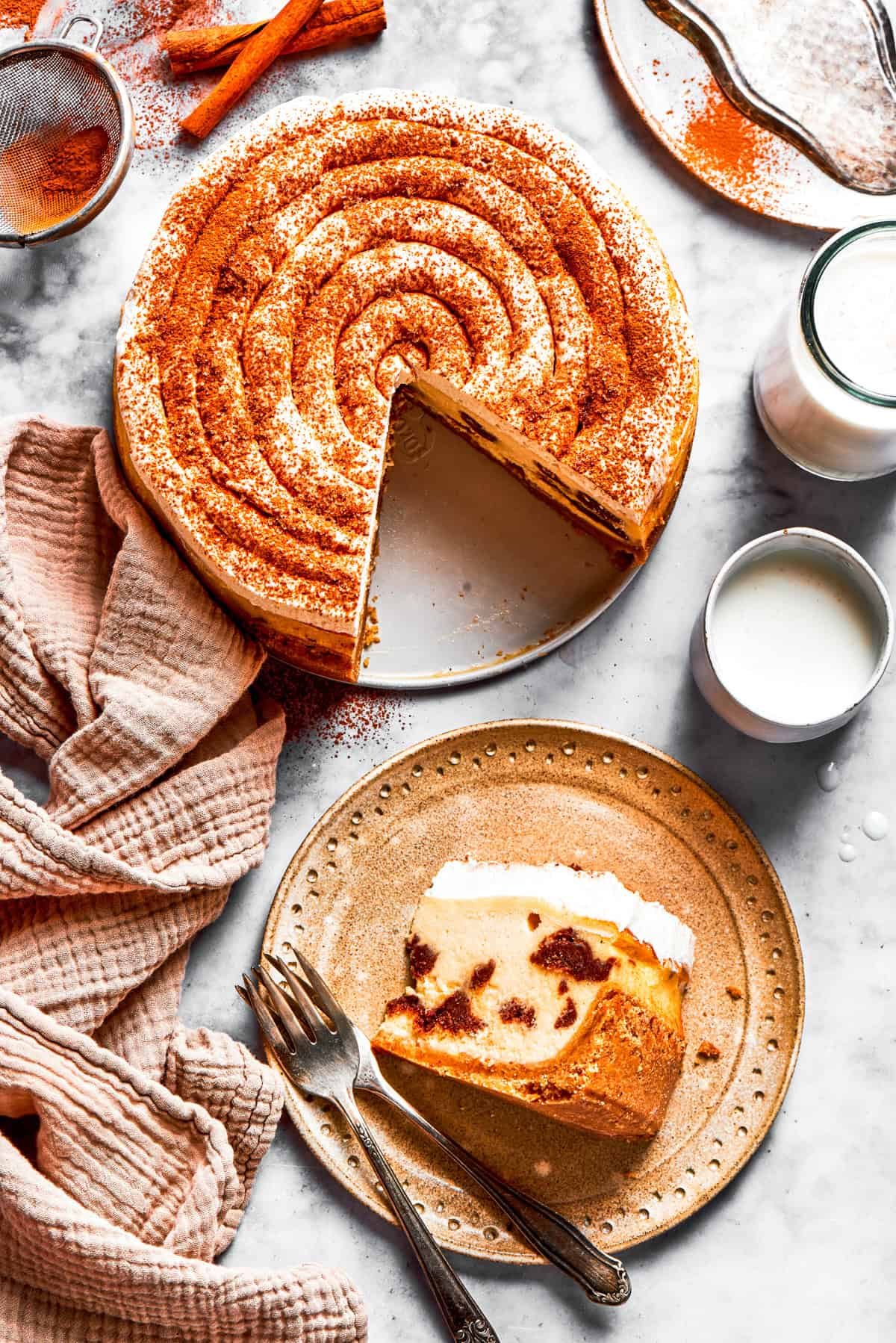 Cinnamon roll cheesecake layers a cinnamon-swirled cheesecake on a crisp and butter cookie crust with a tangy cream cheese frosting on top.