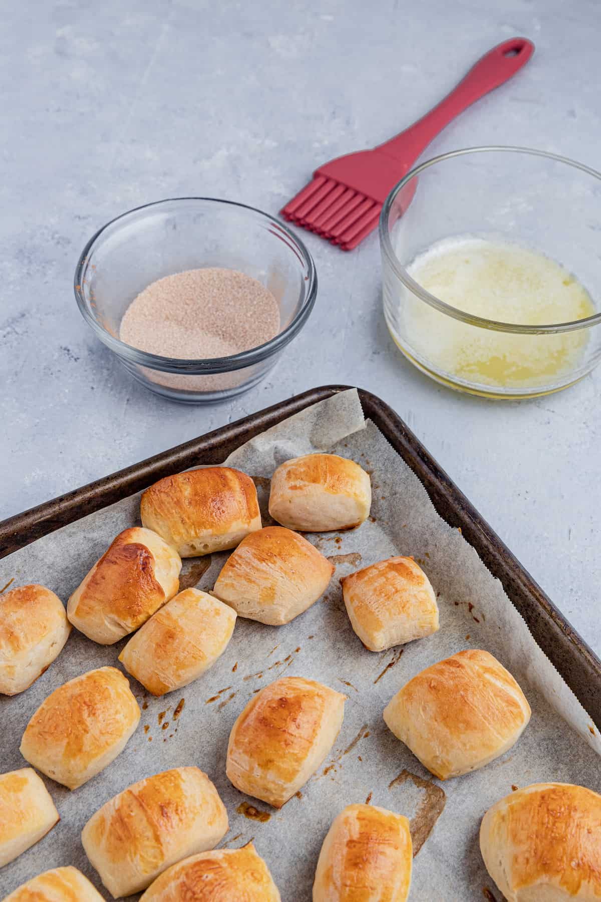 Baked pretzel bites with a bowl of butter and a bowl of cinnamon sugar