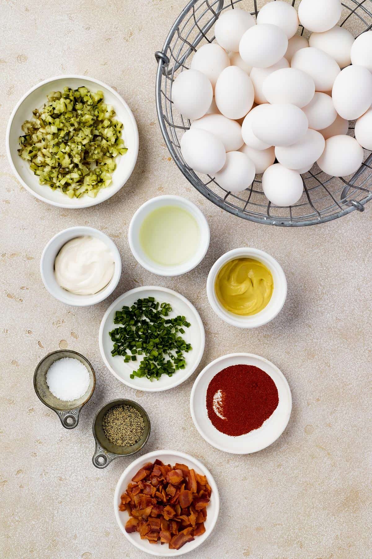 From top left: Chopped pickles, eggs, mayonnaise, pickle juice, dijon mustard, chopped chives, paprika, salt, pepper, chopped bacon.