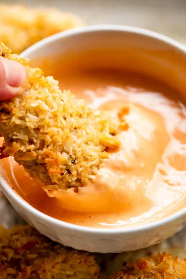 Dipping coconut chicken tenders in sriracha mayo sauce