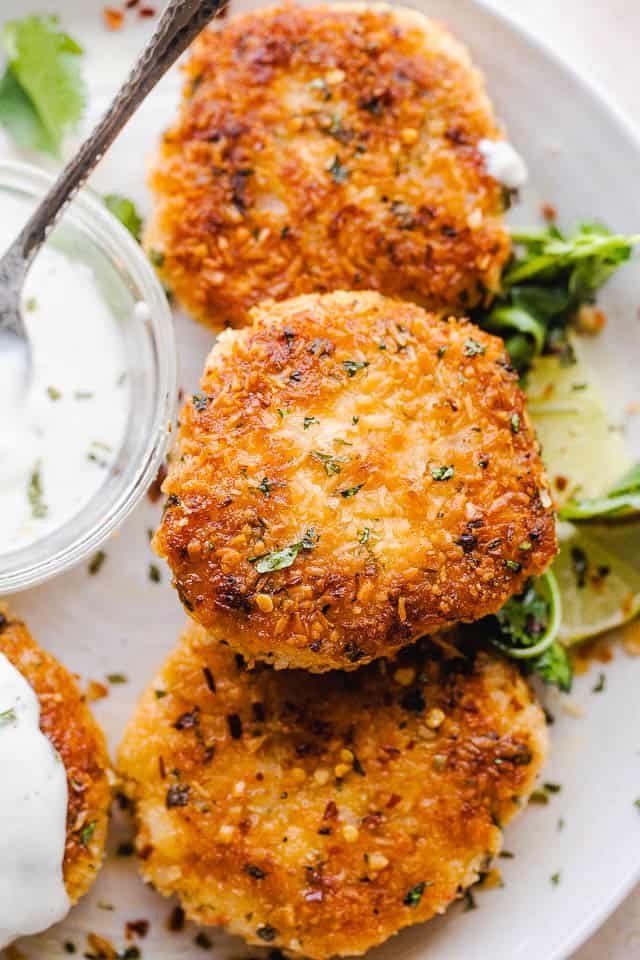 close up overhead shot of plated shrimp cakes on a white serving plate and a bowl of sauce