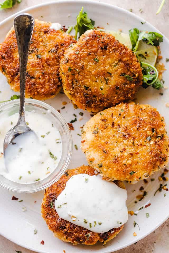 plated shrimp cakes on a white serving plate and a bowl of sauce