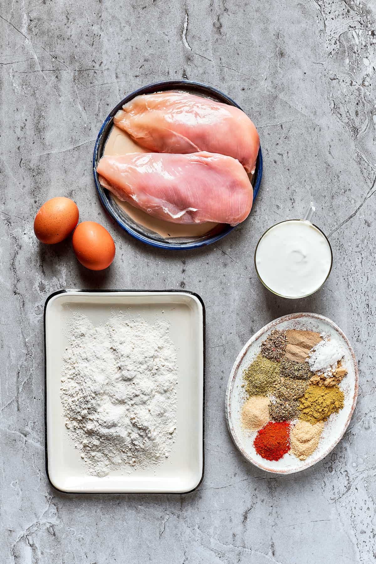 From top: Chicken breast, buttermilk, spices and seasonings, flour, and eggs.