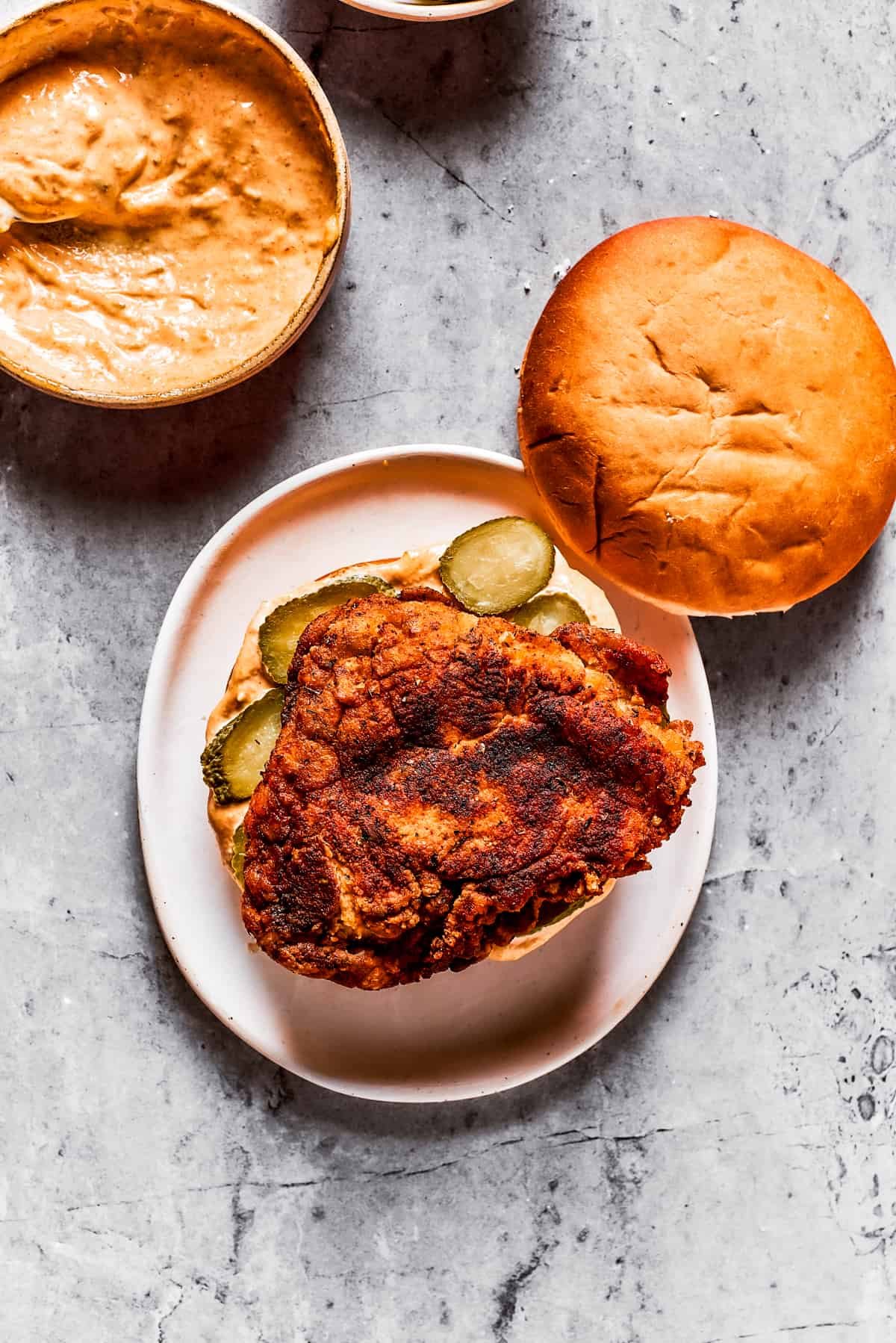Assembling a copycat KFC chicken sandwich on a plate.