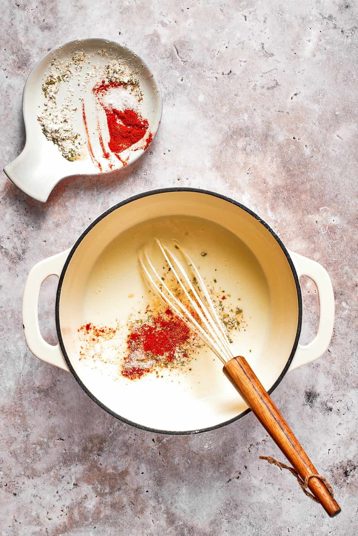 Spices are whisked into a pot of sauce.