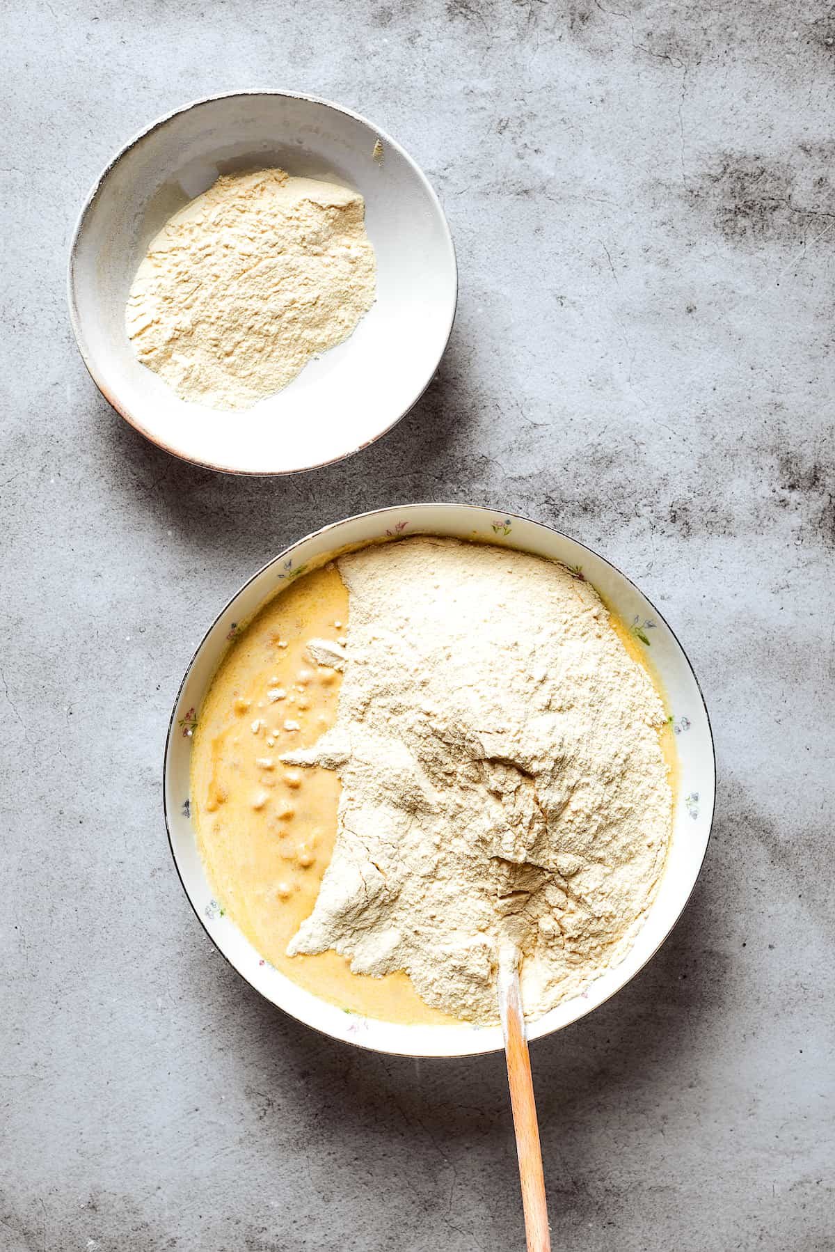Cornbread mix is added to a bowl of corn souffle base.