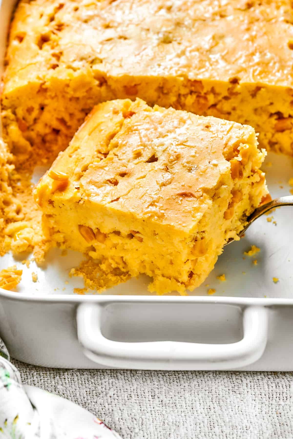 A cut-out square of corn souffle inside a white baking dish.