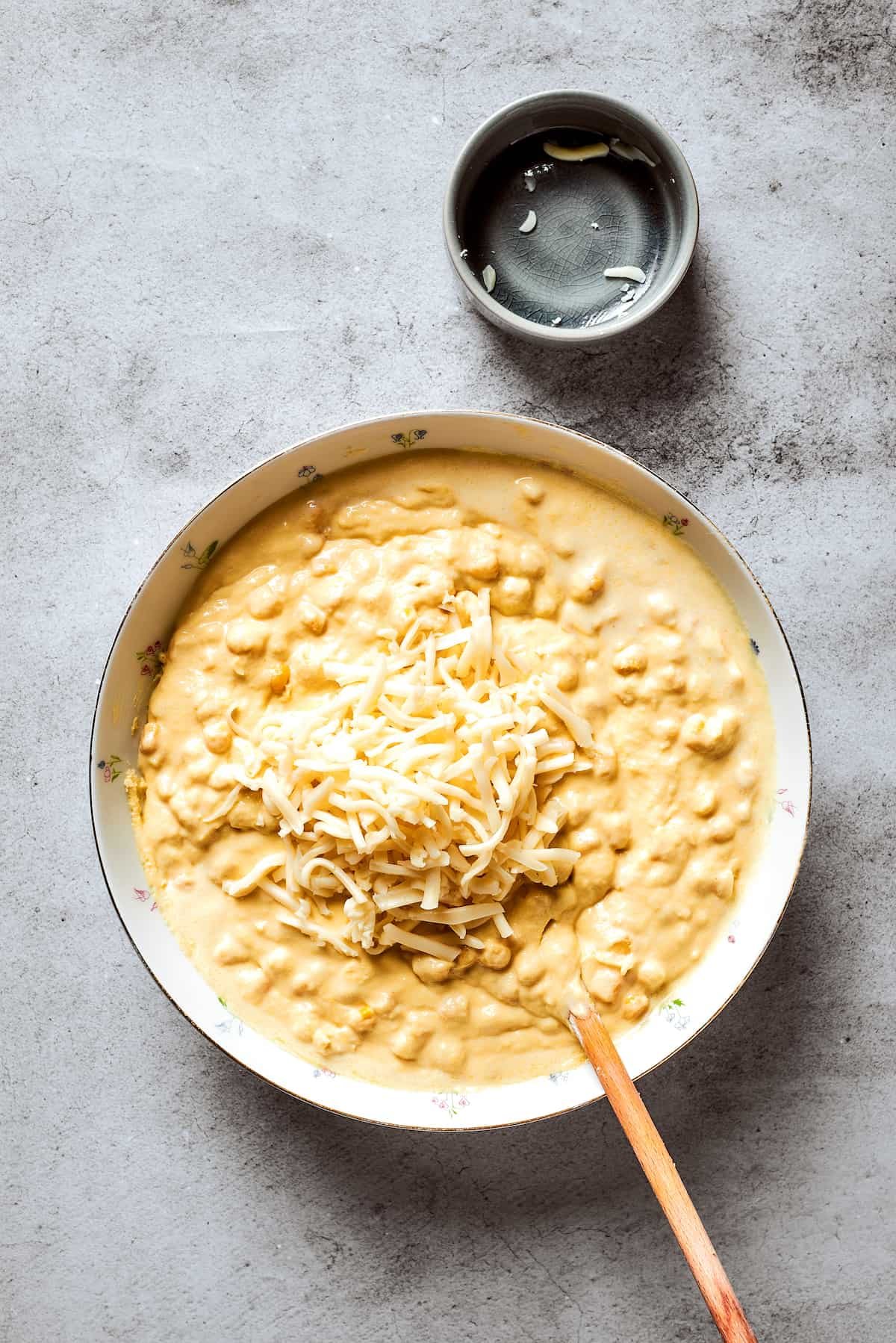 Cheese is added to a bowl of corn souffle base.