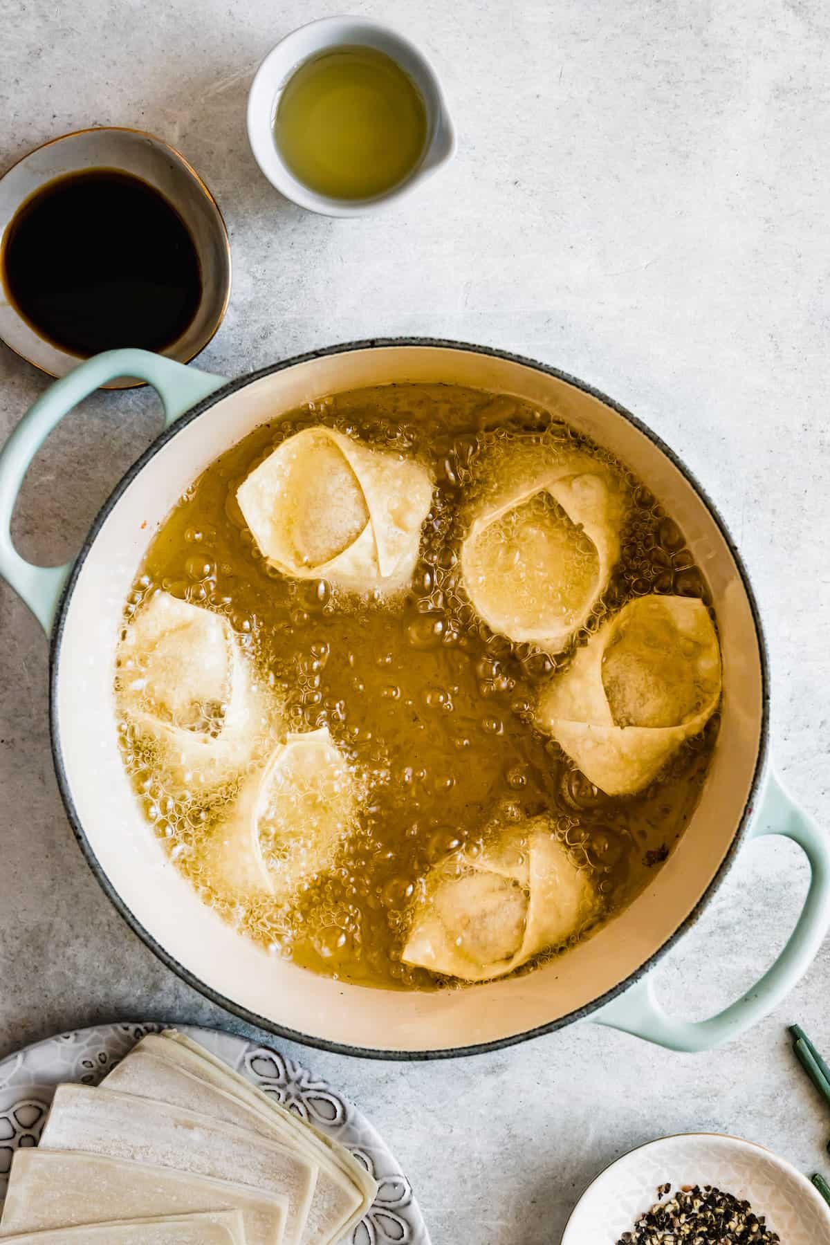 Crab rangoon wontons being fried in oil