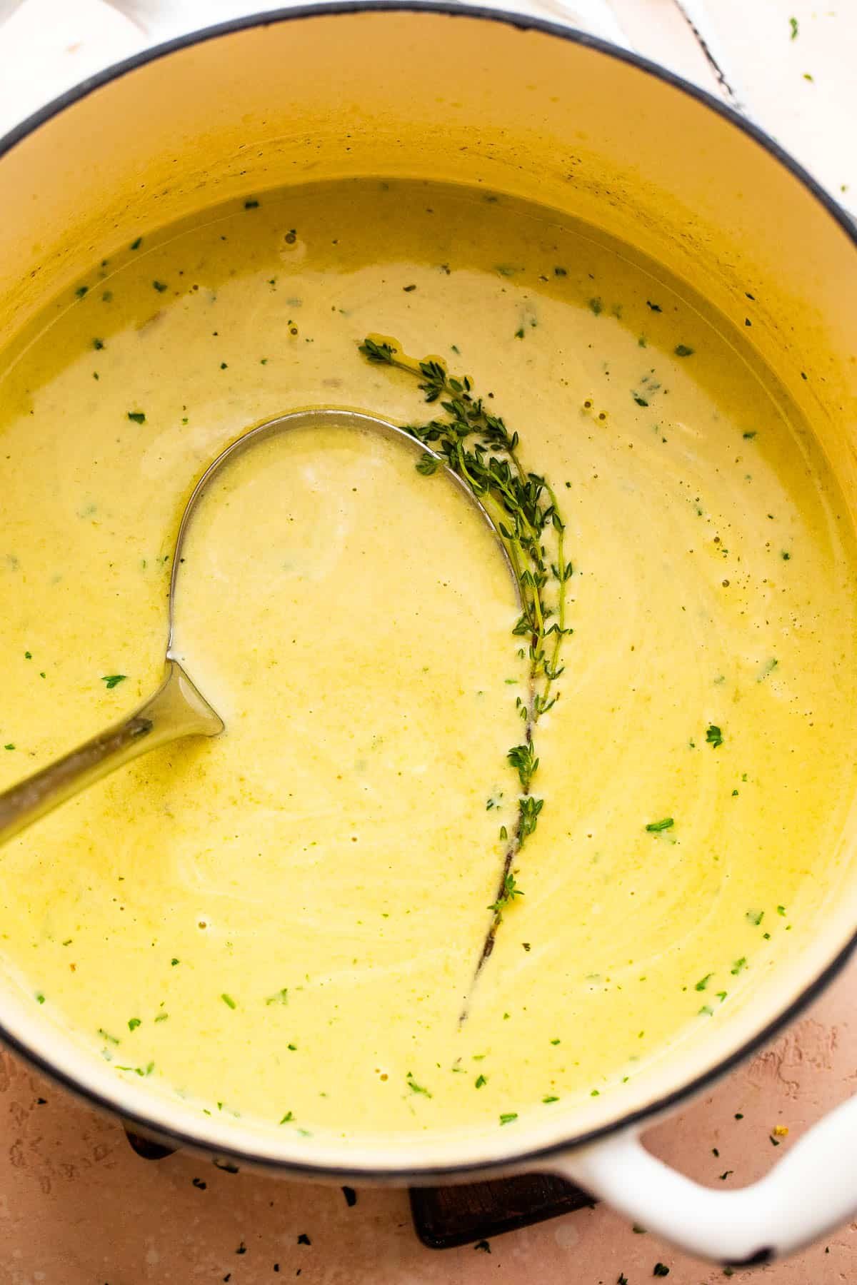 cream of asparagus soup in a pot with a ladle inside it.