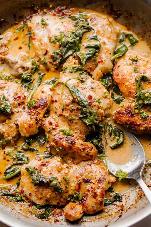 overhead shot of boneless skinless chicken thighs in a creamy sauce with spinach