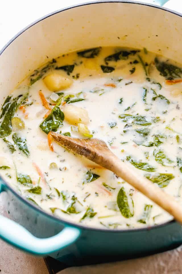 side shot of creamy gnocchi soup with spinach and chicken pictured in dutch oven