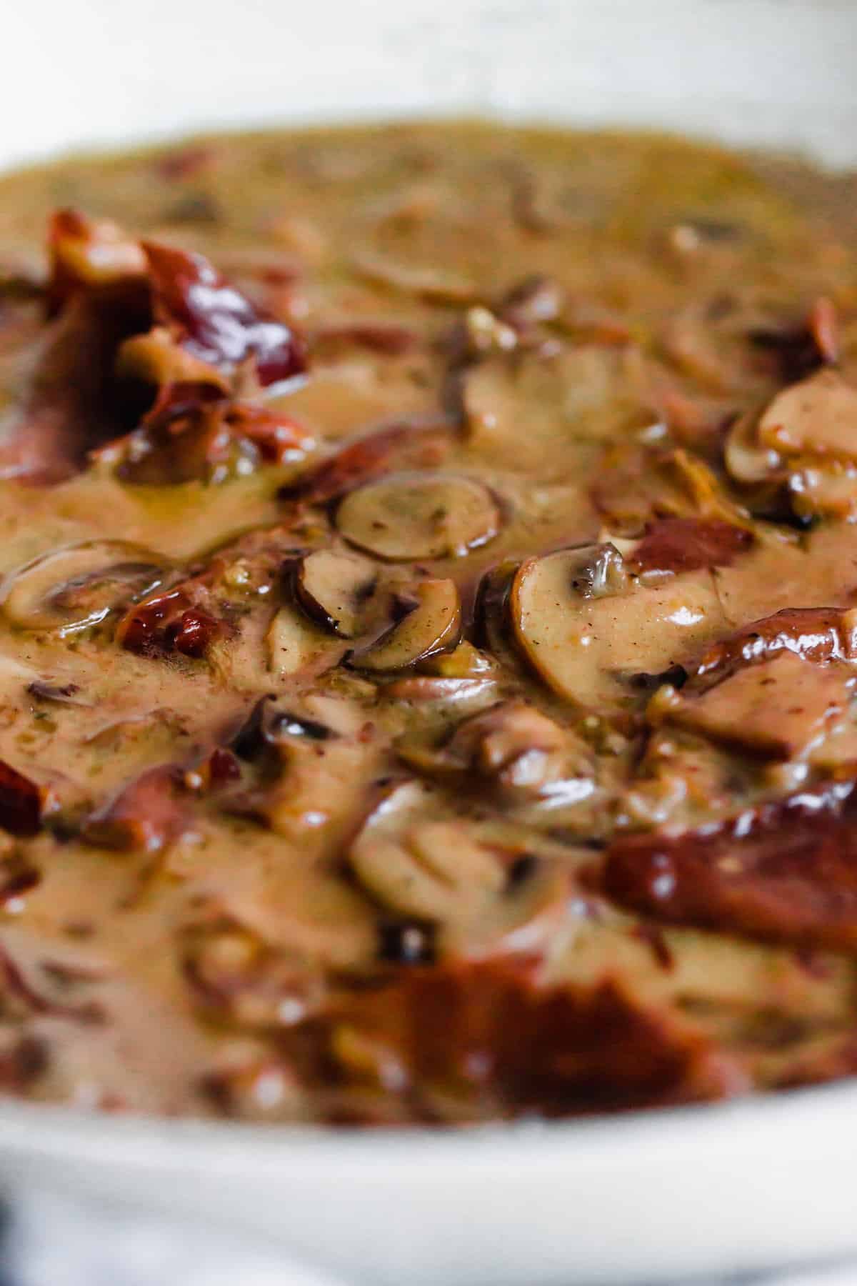Mushrooms and proscuitto cooking in a creamy sauce.