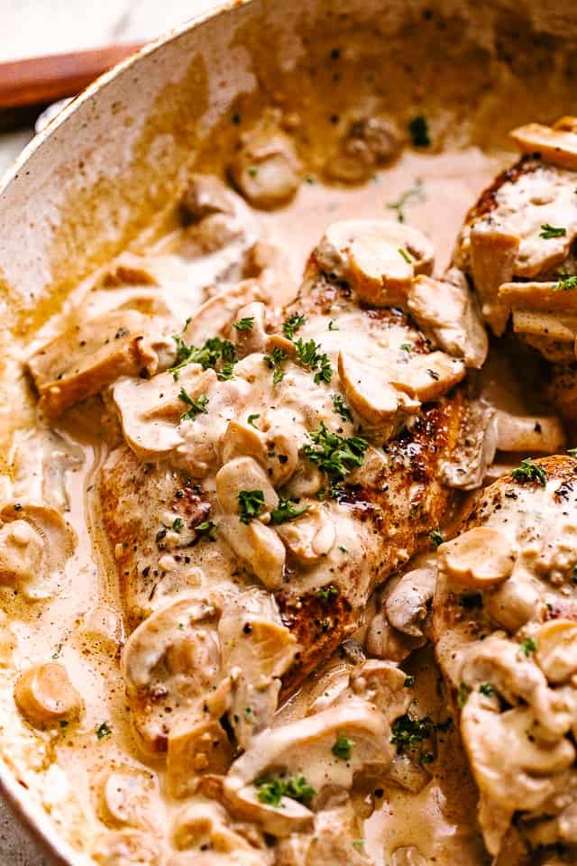 Creamy mushroom chicken in a skillet garnished with fresh herbs