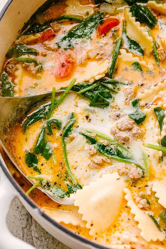 Close up image of a soup with spinach and ravioli.