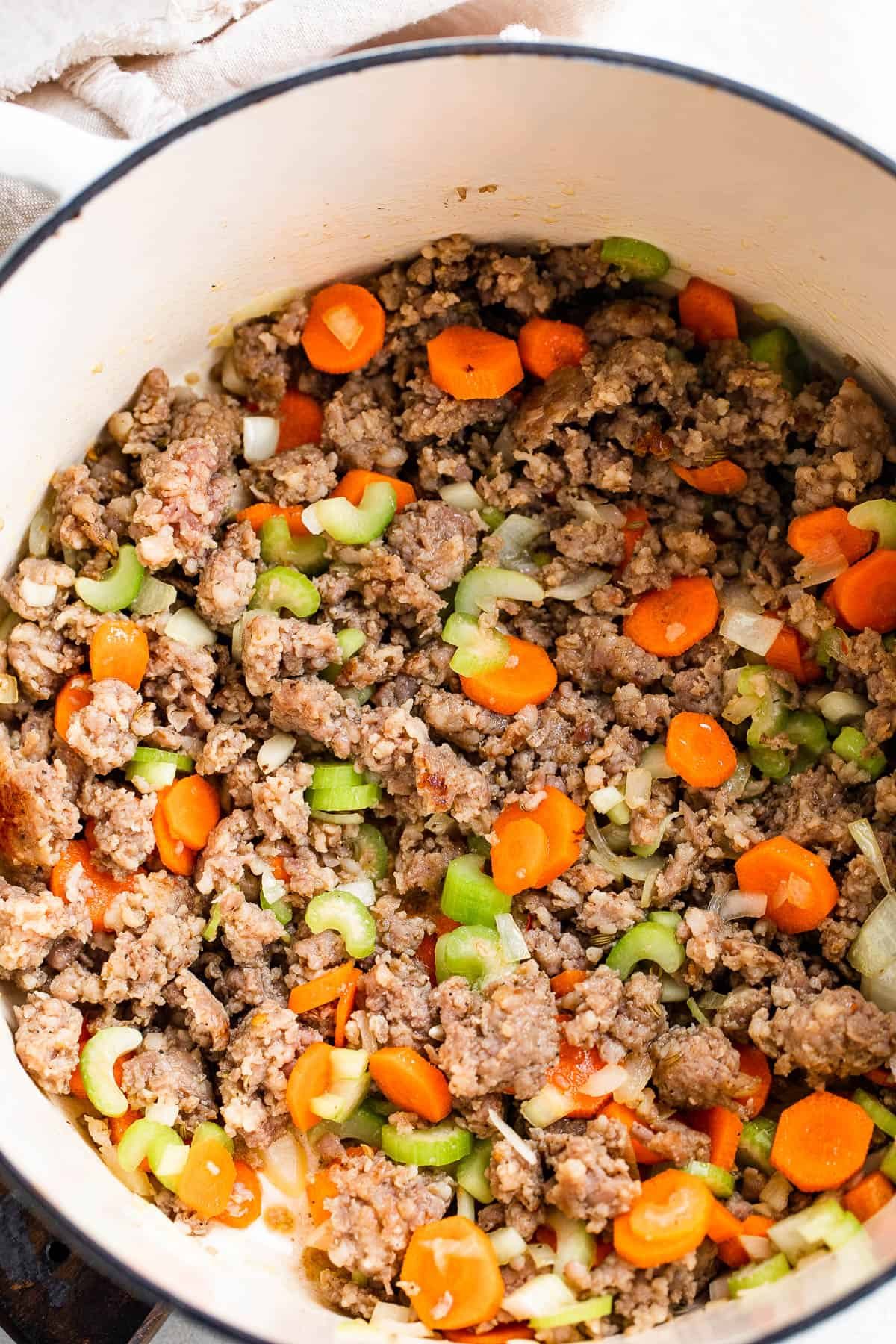cooking Italian sausage in a white dutch oven