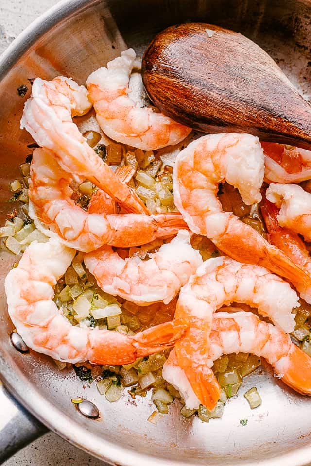 Shrimp sauteing in a pan with garlic.