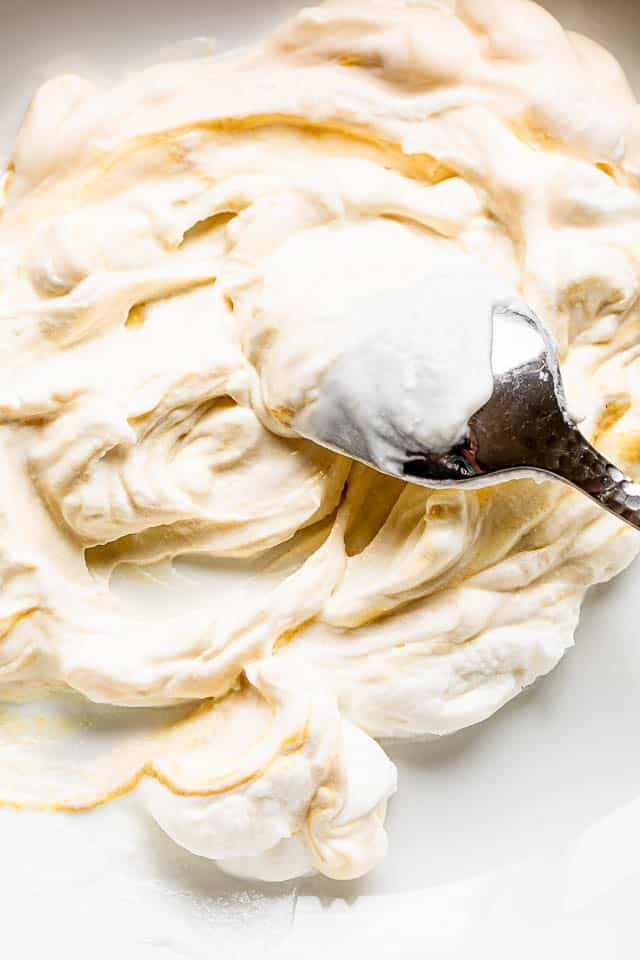 silver spoon stirring and preparing a creamy dressing in a white bowl