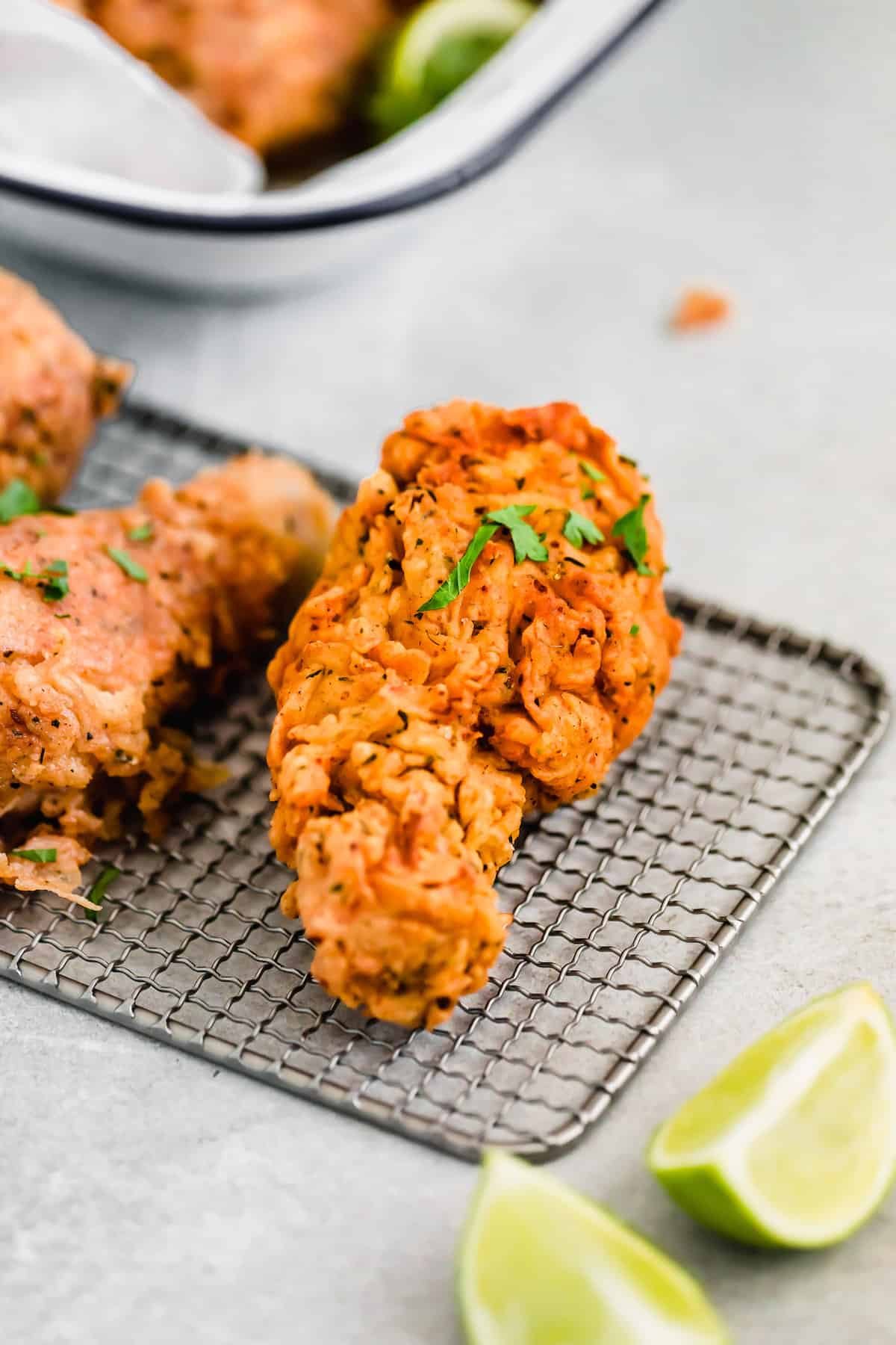 A Piece of Fried Chicken Resting Beside Two Lime Slices