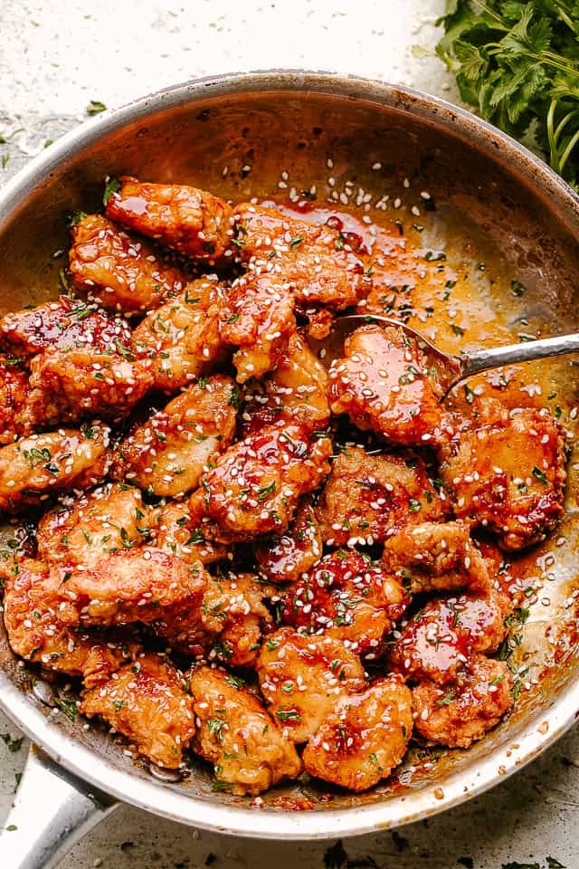 Crispy Honey Sesame Chicken being stirred in a pan