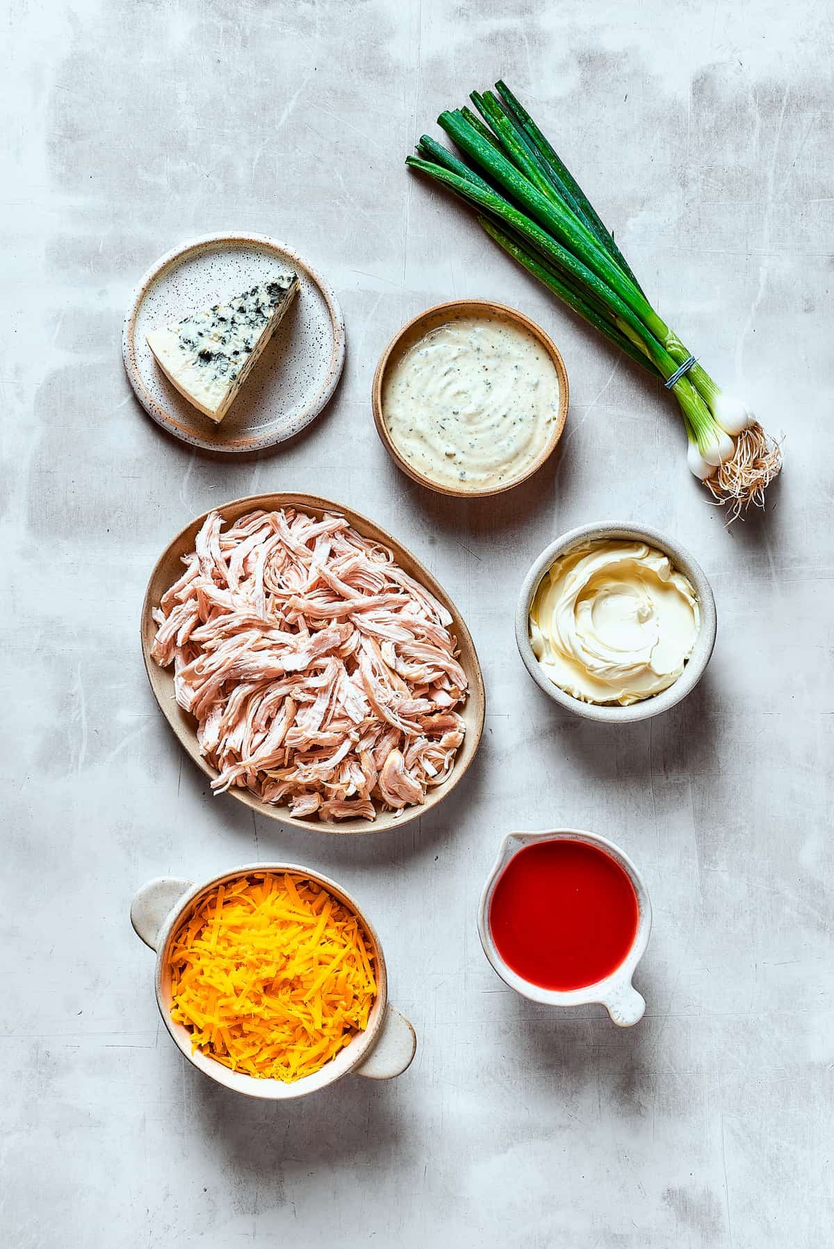 Ingredients for crockpot buffalo chicken dip, arranged on a table.