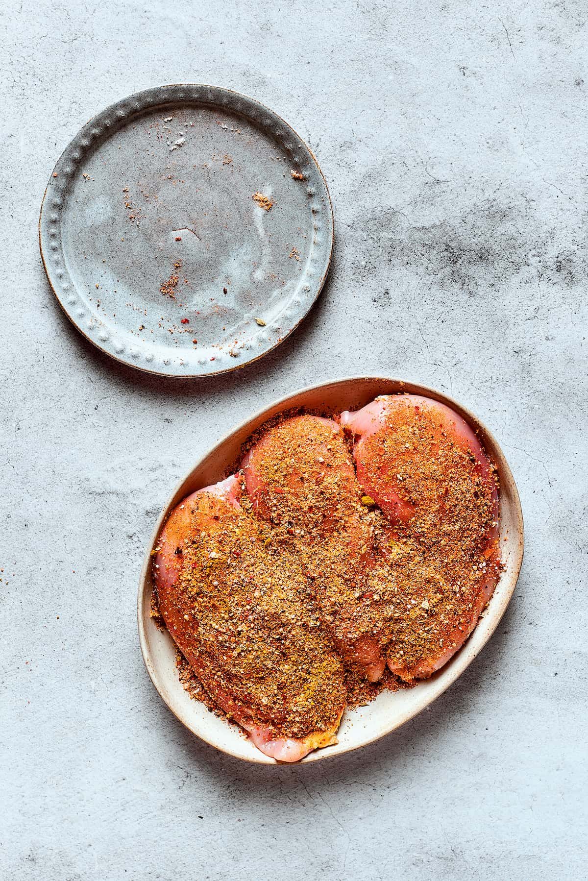Seasoned chicken breasts on a plate.