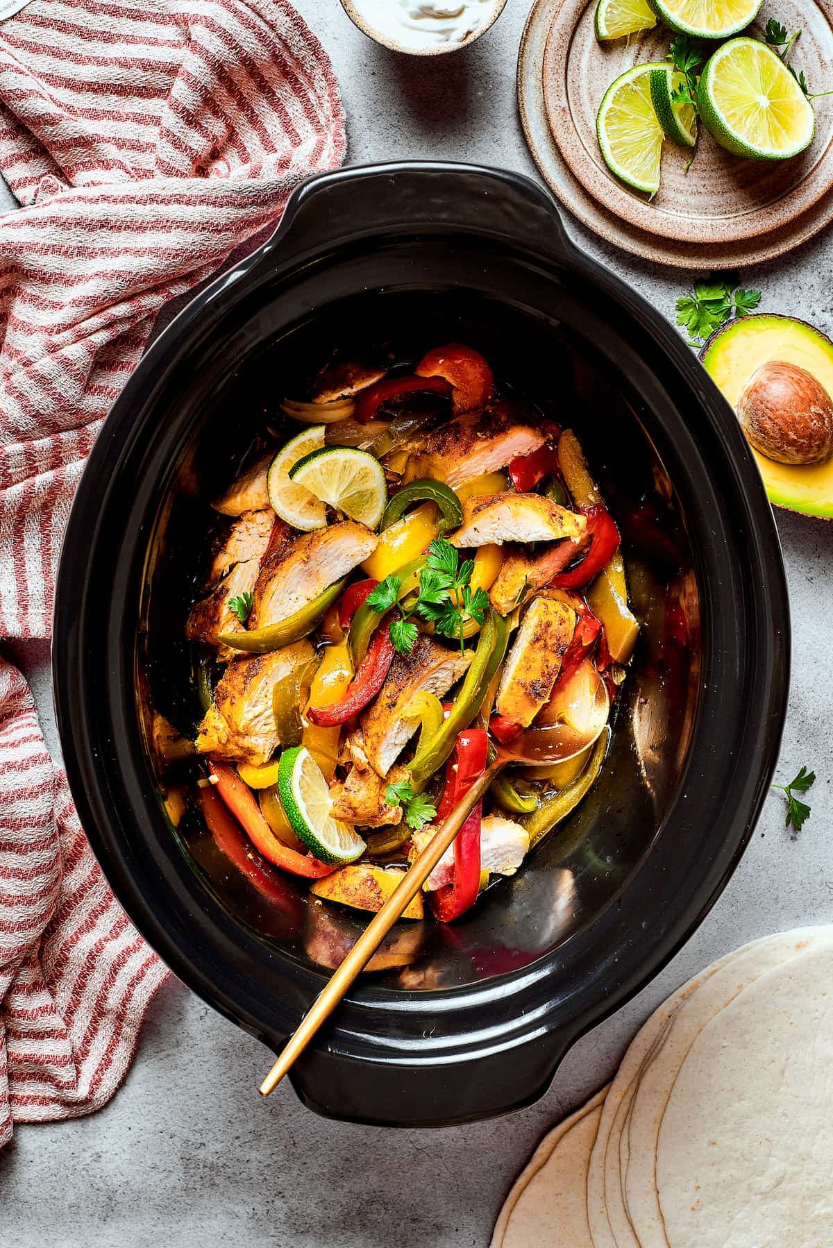 A slow cooker of Southwest-style chicken with bell peppers and onions.