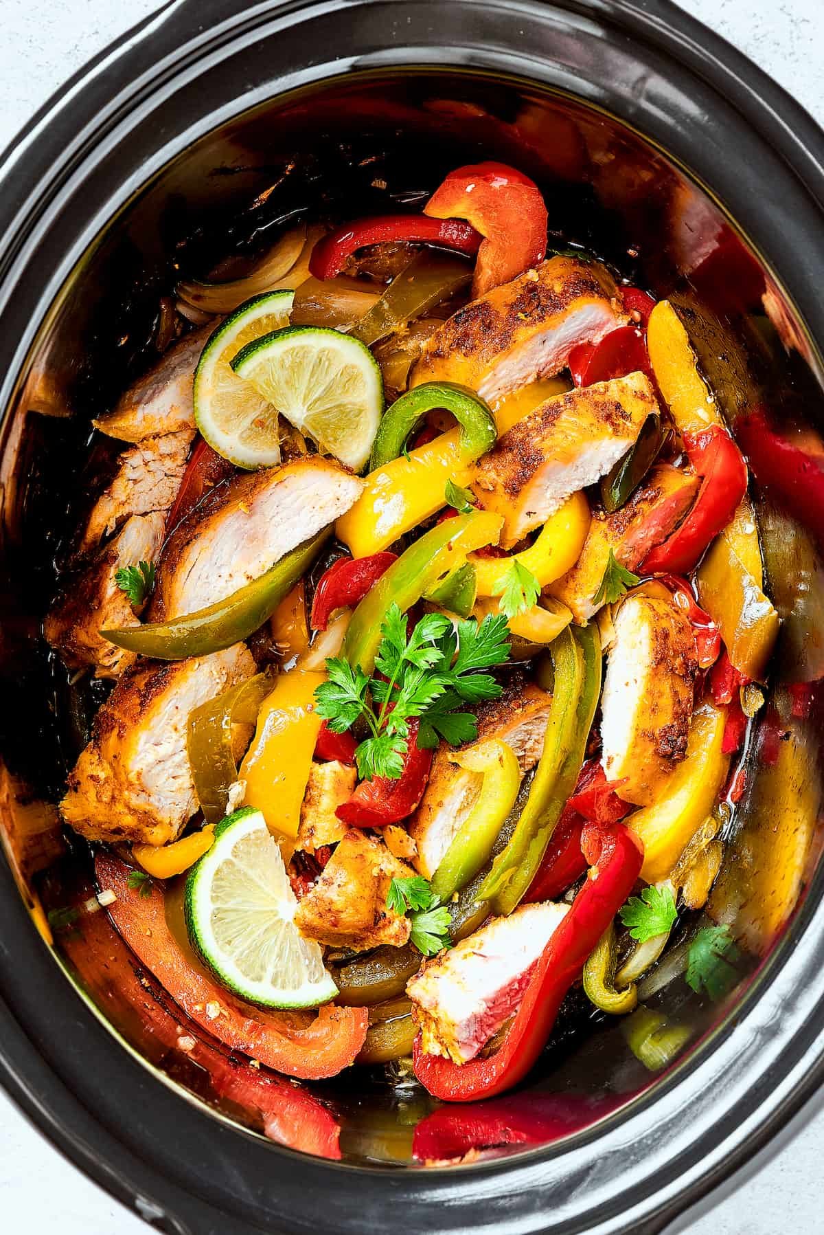 Crockpot chicken fajitas in a slow cooker insert.