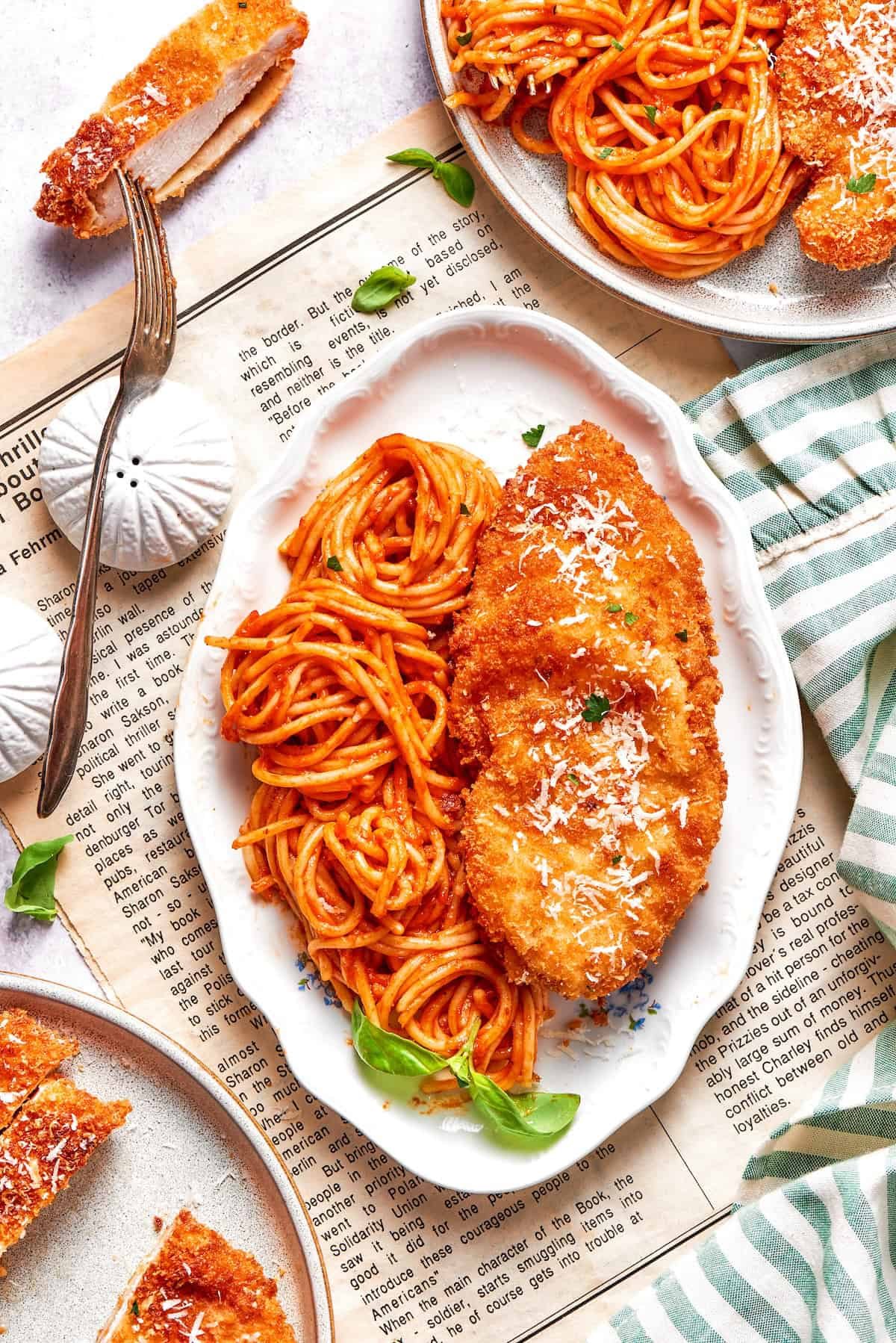 A platter of spaghetti and marinara sauce and pieces of crusted chicken romano.