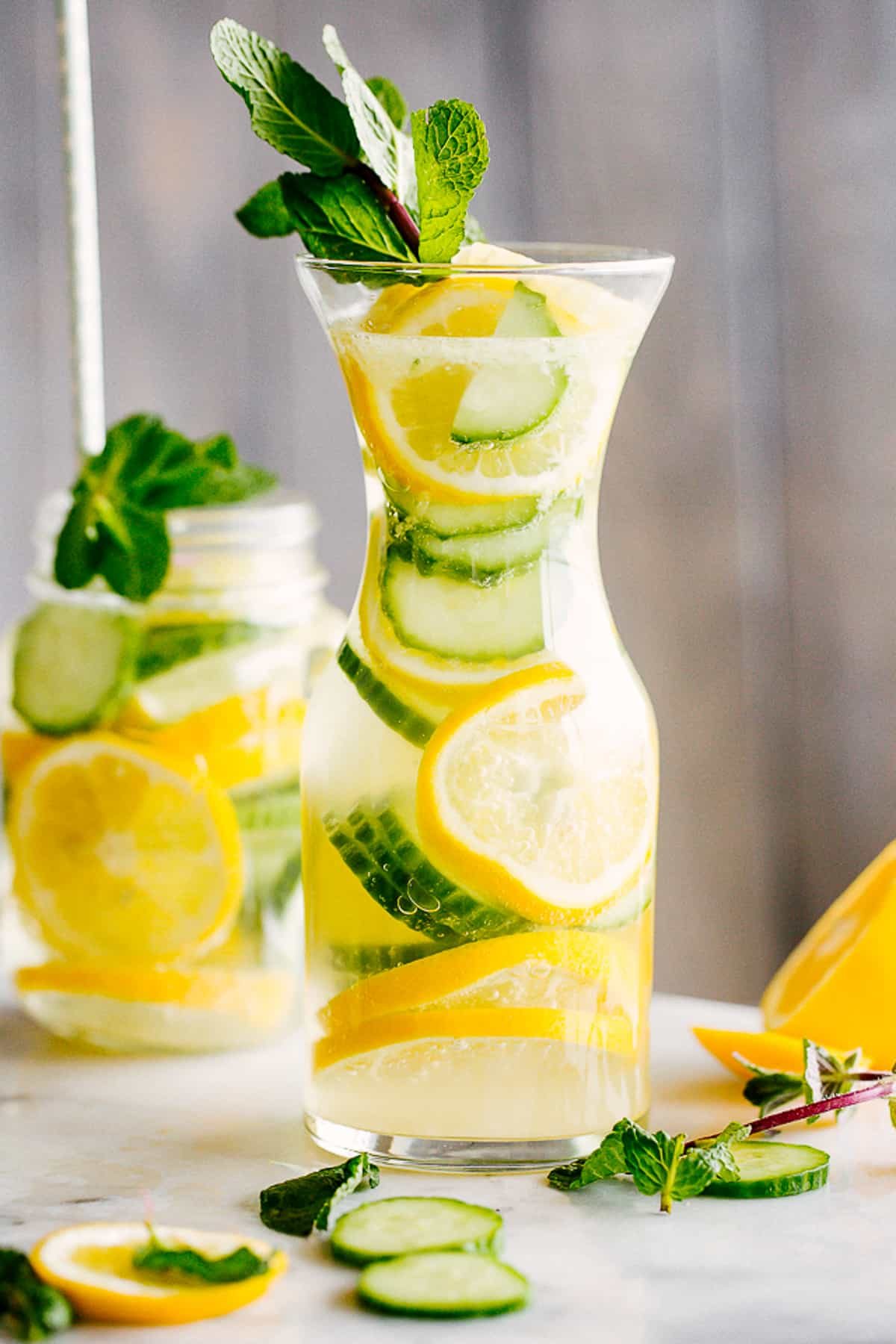 lemon cucumber water served in a mason jar with handle, and in a tall carafe