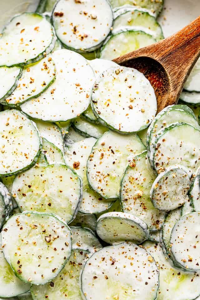 top view close up shot of scooping out cucumbers with a wooden spoon