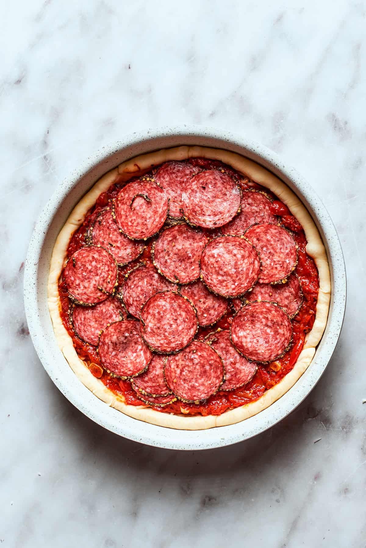 Pepperoni slices are added to the pizza.