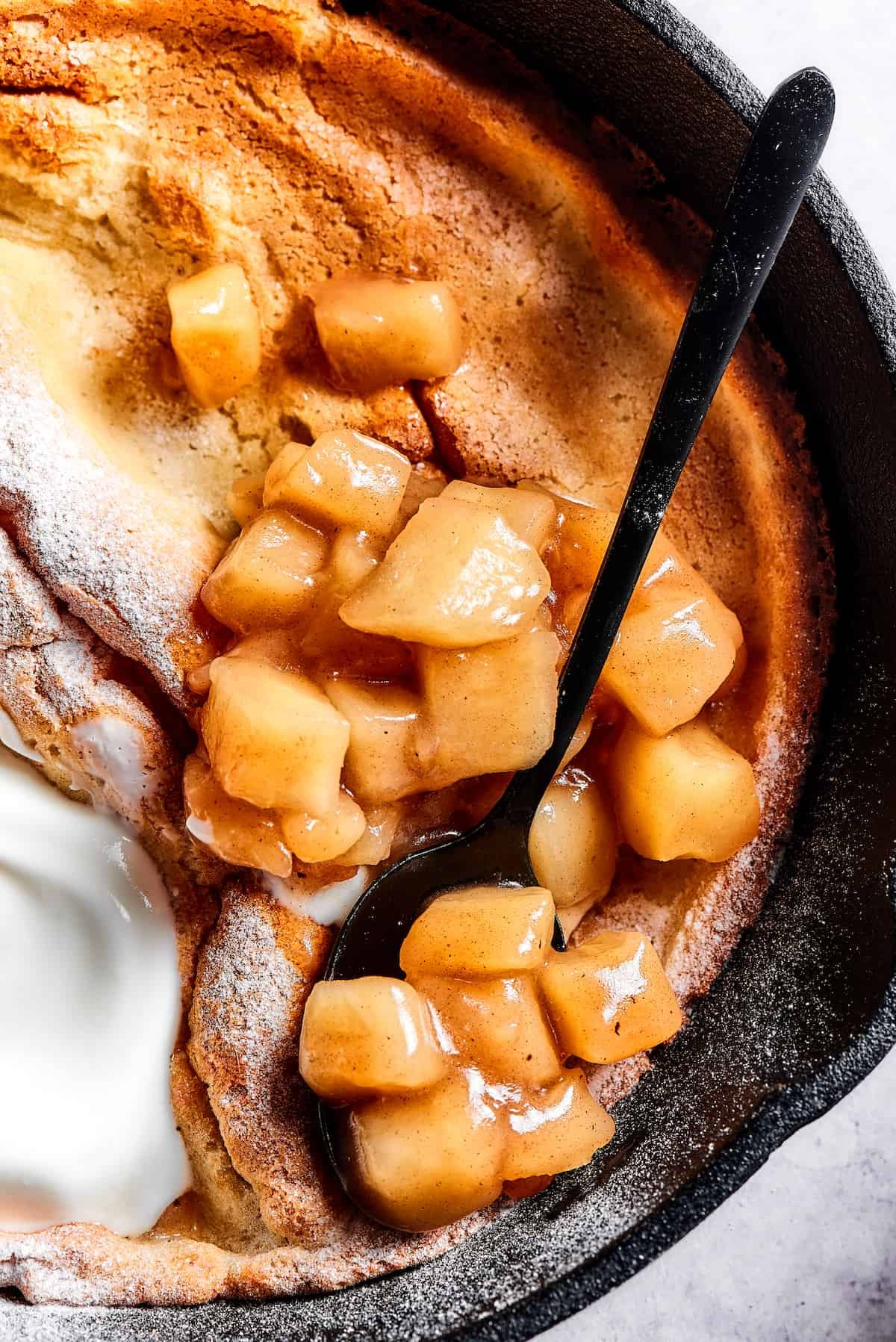 A skillet pancake with apples and creamy topping.
