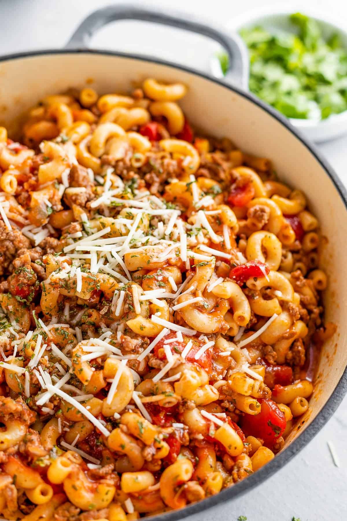 A Gray Pot Full of American Goulash Topped with Chopped Parsley and Grated Parmesan