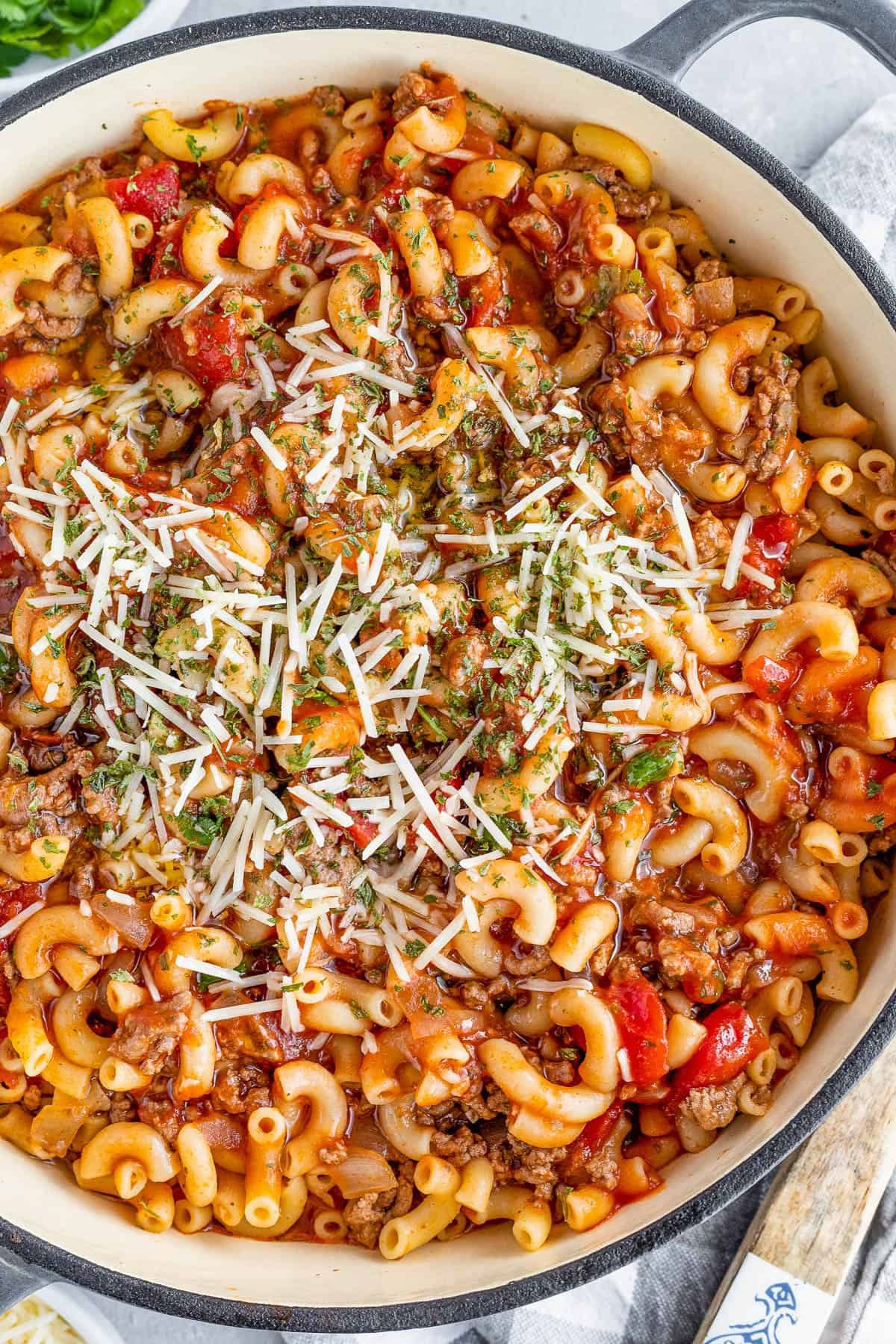 overhead shot of a Gray Pot Full of American Goulash Topped with Chopped Parsley and Grated Parmesan