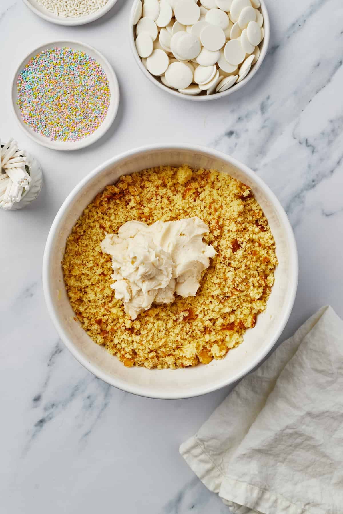 Cake crumbs and frosting in a mixing bowl.