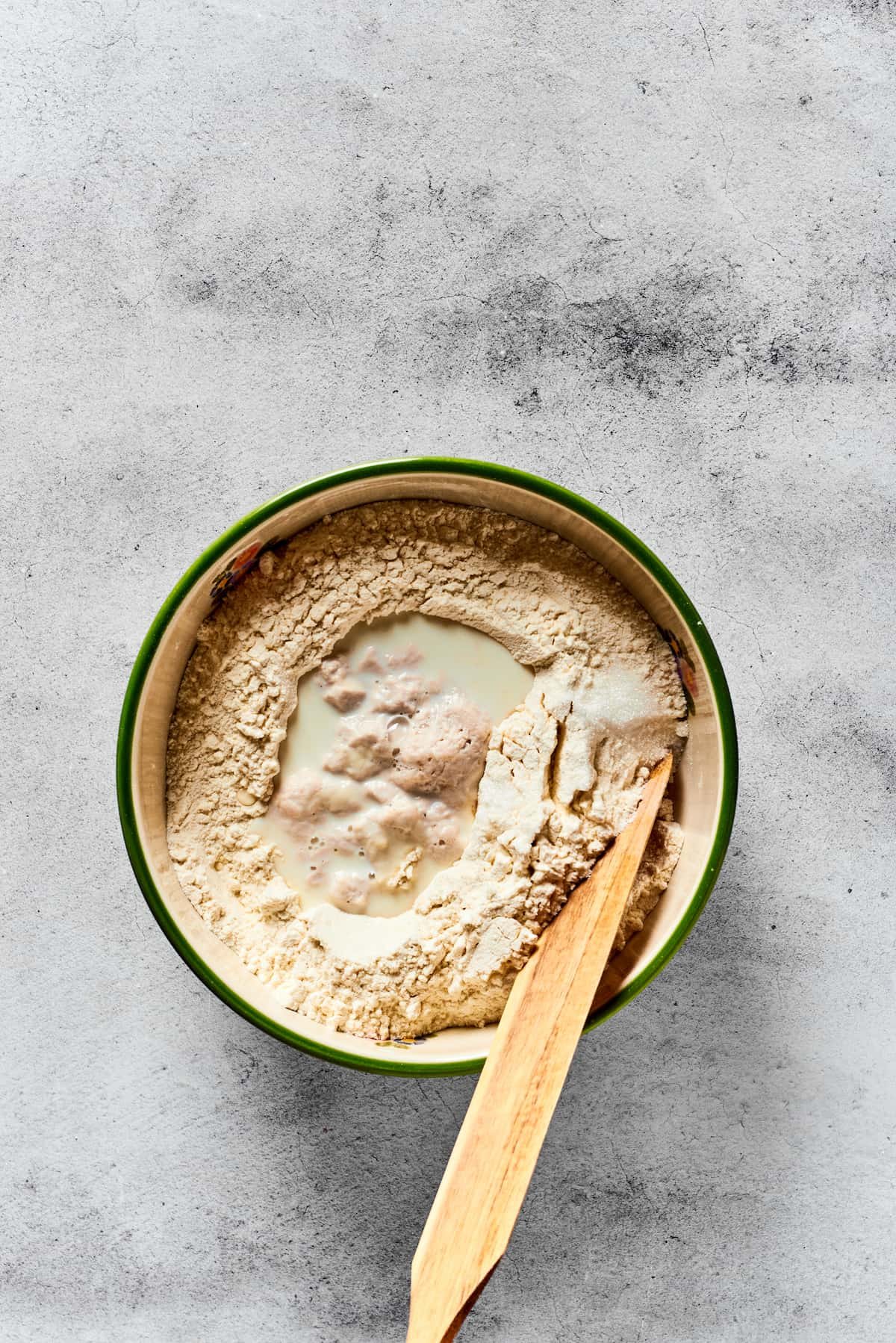 MIxing together calzone dough in a mixing bowl.