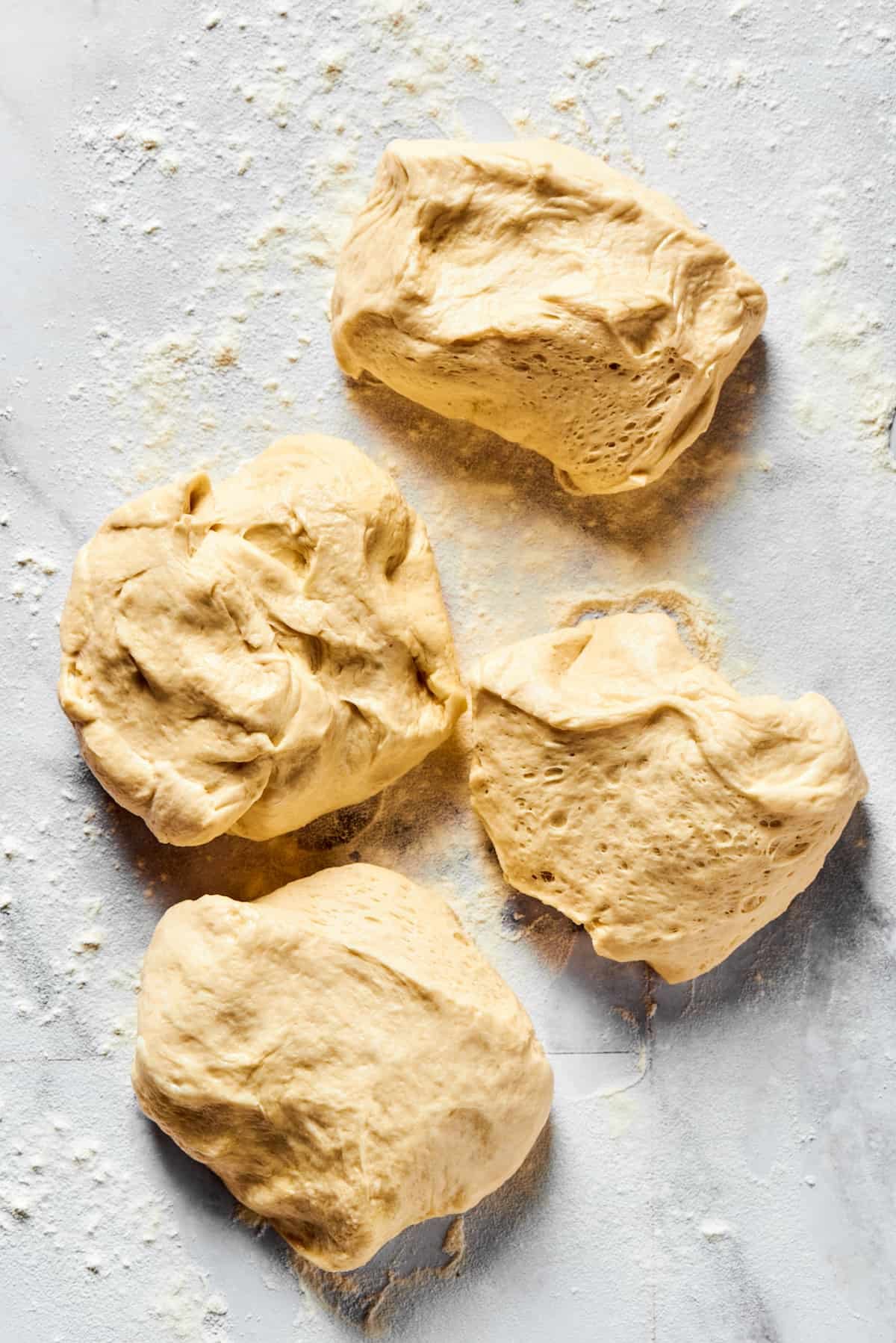 Dough portioned into 4 pieces on a floured work surface.