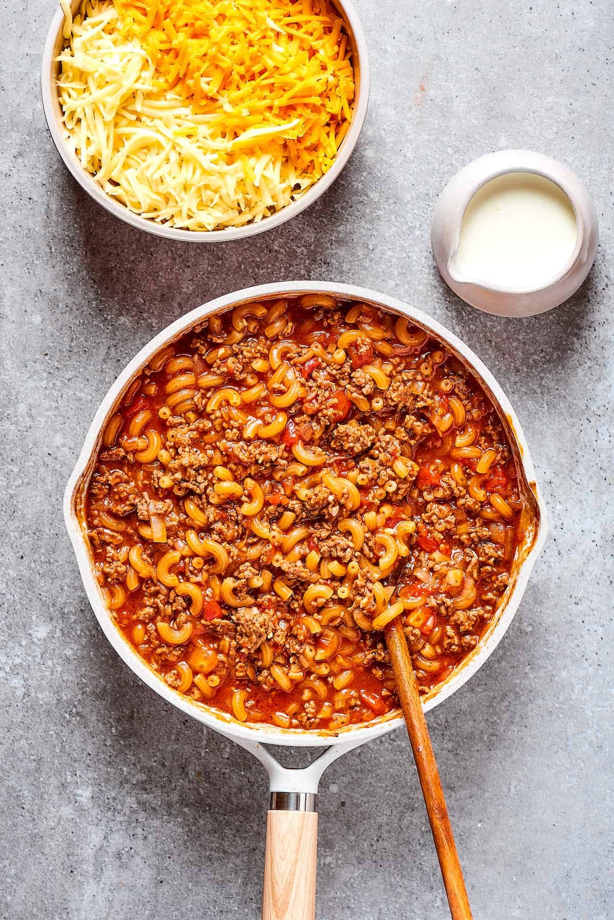 Macaroni pasta cooking in a skillet with sauce and beef.