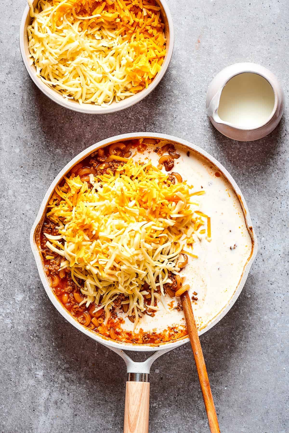 Stirring cream and cheese into a skillet dish.
