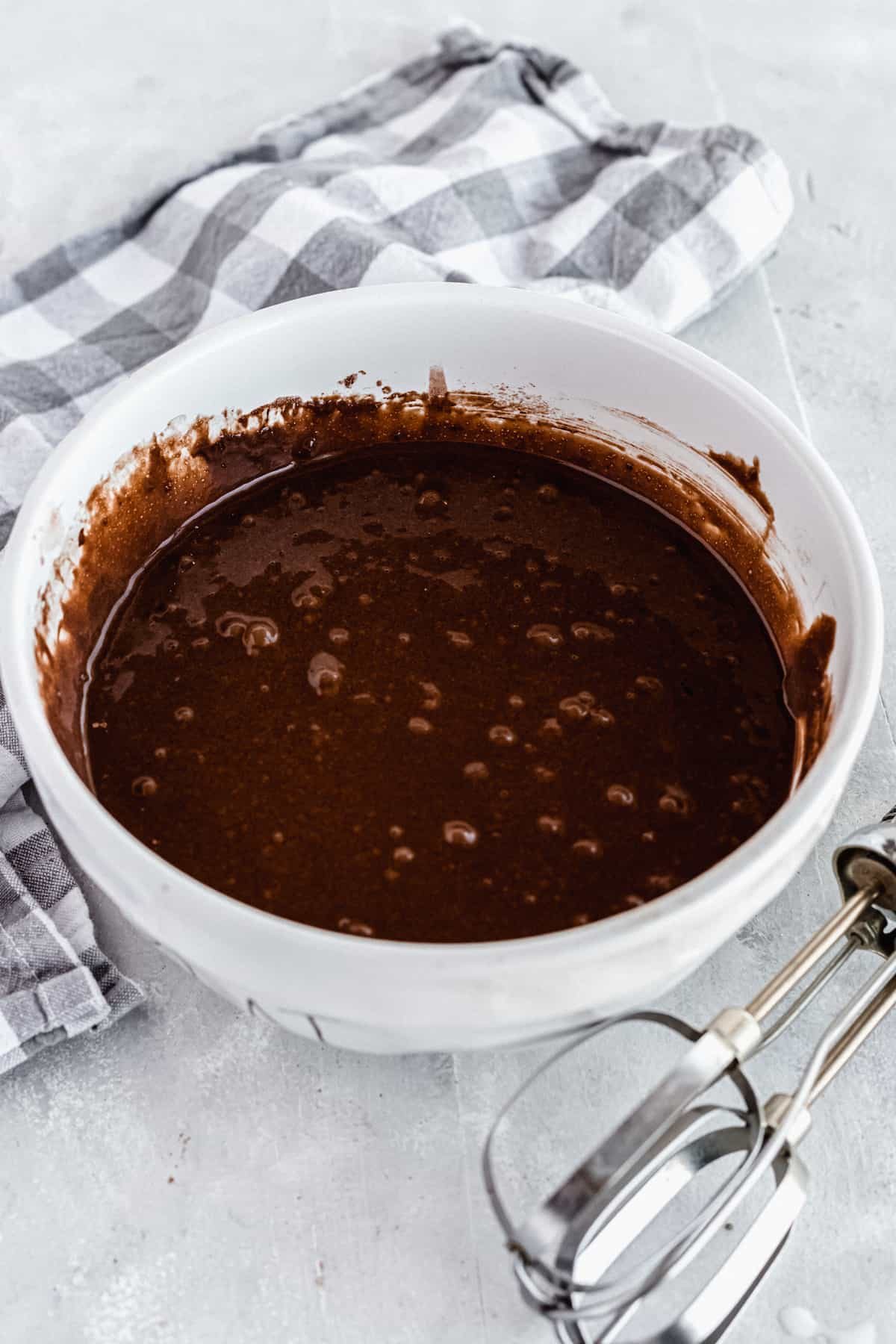 A White Bowl Filled with Cake Batter Beside a Metal Whisk Attachment