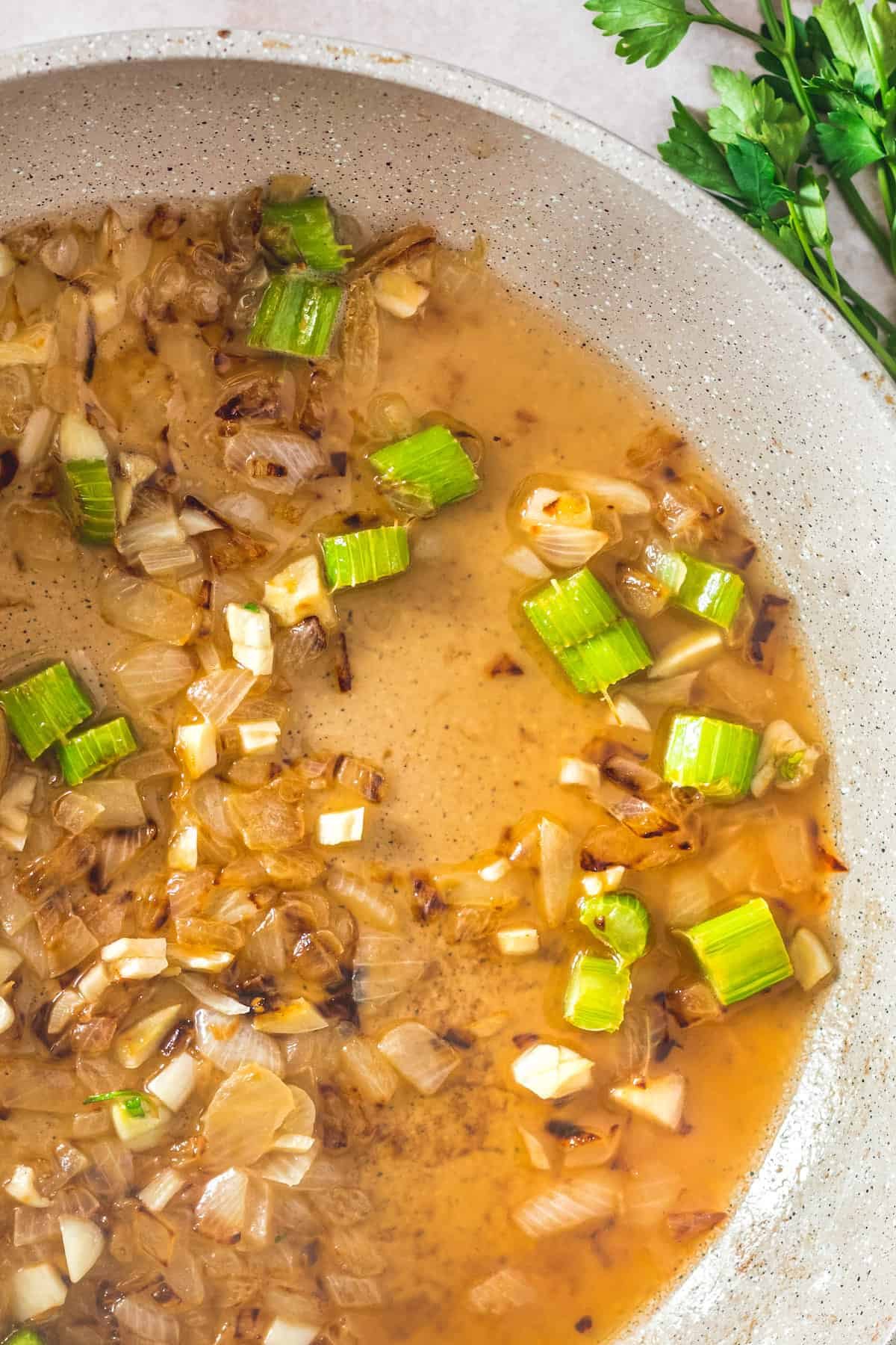 A ceramic skillet with a mixture of chopped vegetables and wine.