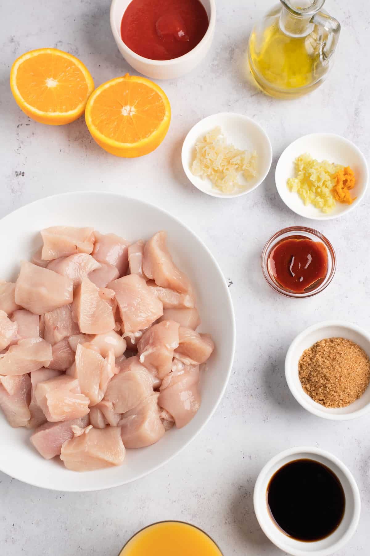 Clockwise from top: Tomato paste, oil, grated ginger, minced garlic and orange zest, sriracha sauce, soy sauce, orange juice, chicken