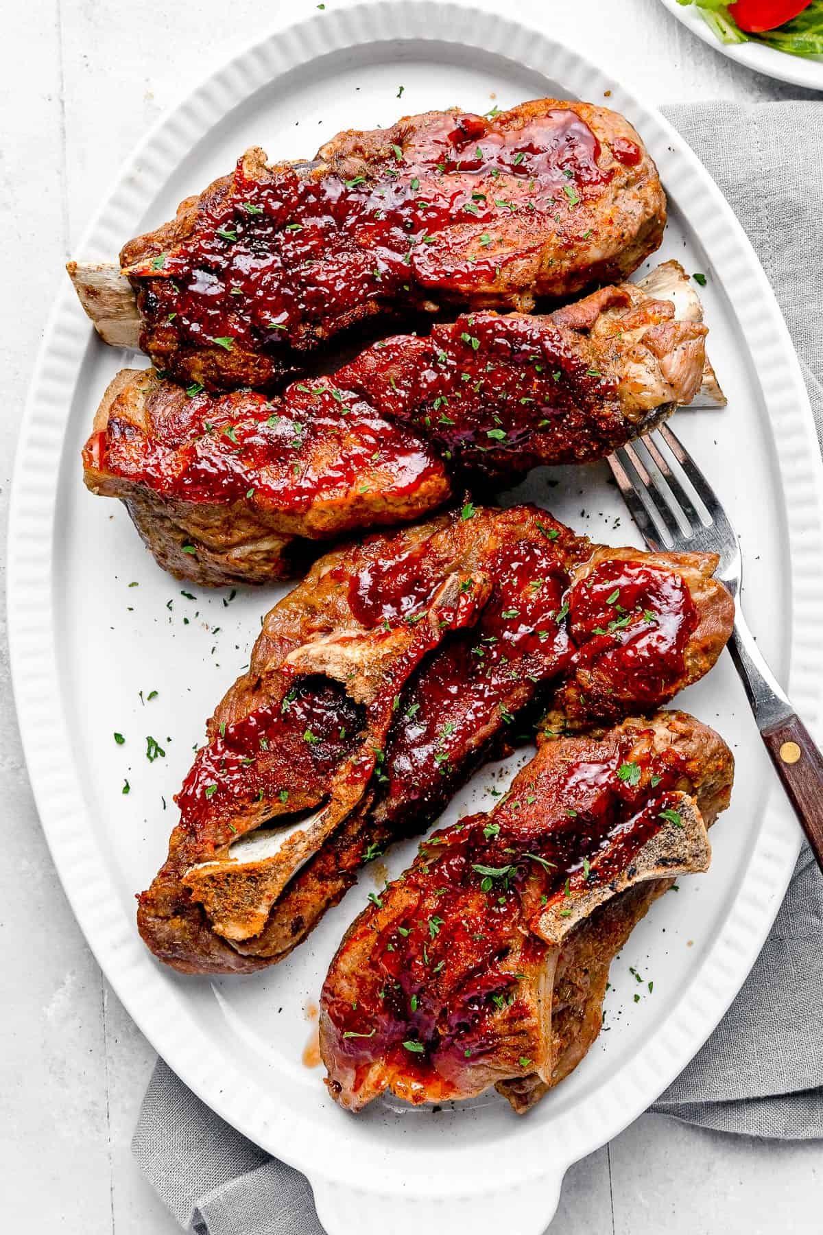 Four Instant Pot Ribs Garnished with Chopped Parsley on a White Plate