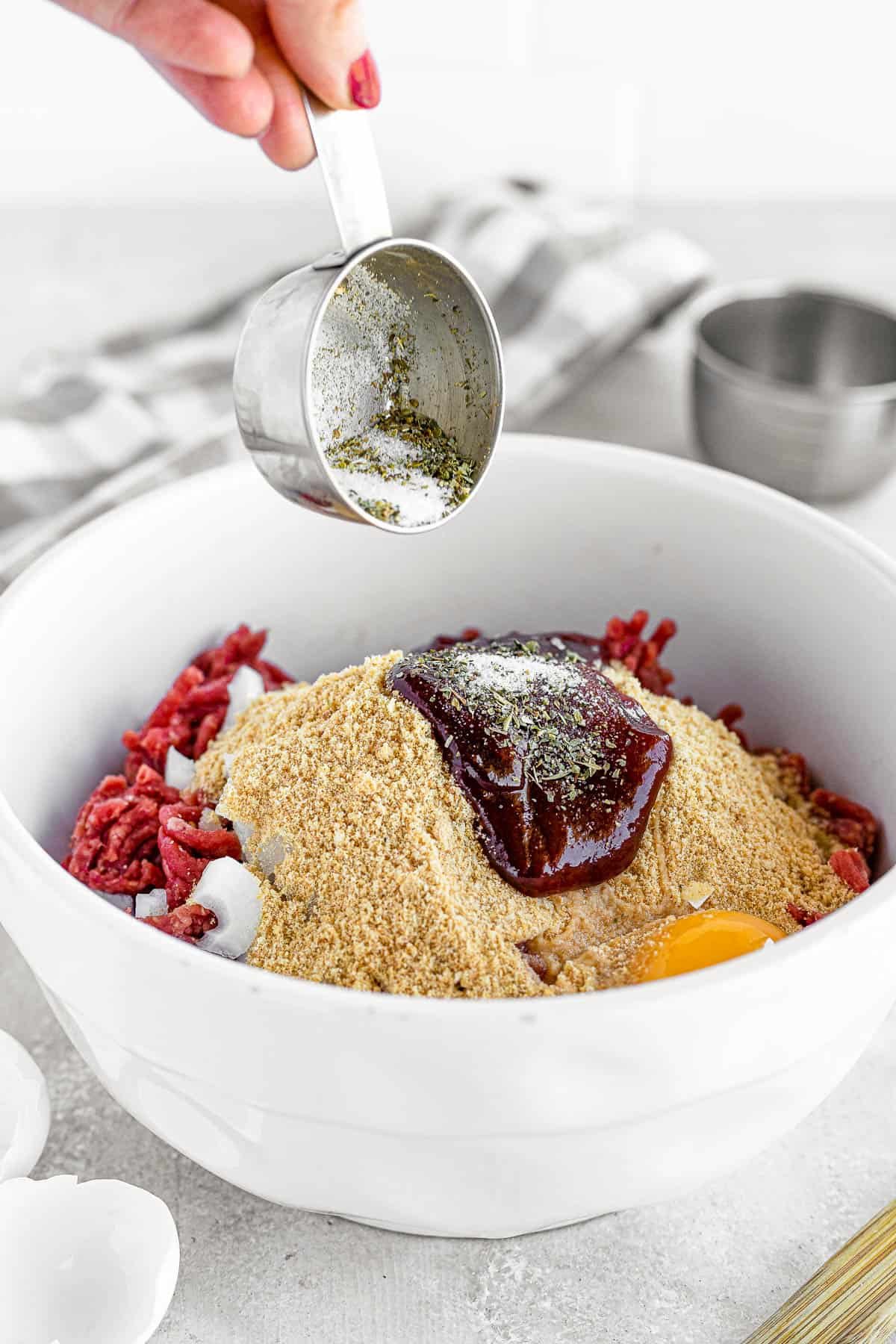 A Bowl of the Meatloaf Mixture Beside a Glass Pan on a Gray Surface