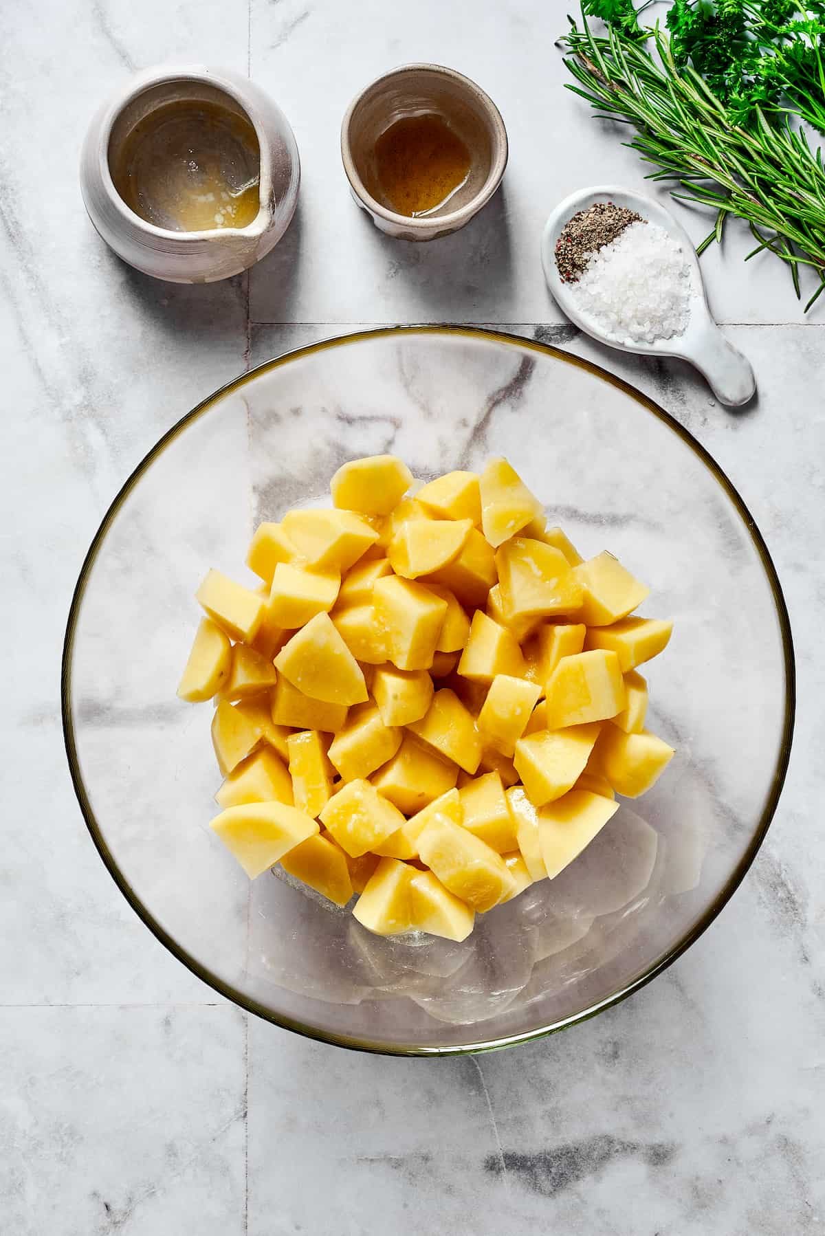 Raw, cut-up potatoes in a mixing bowl.