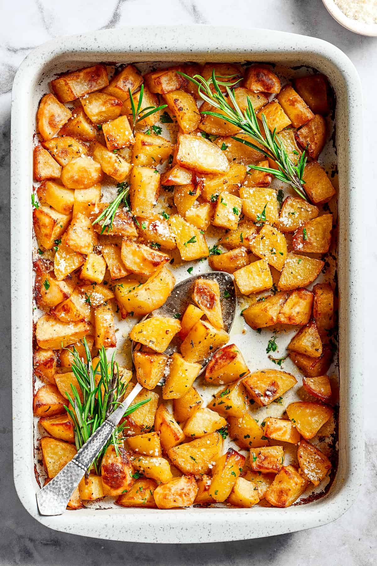 A large baking dish full of baked, seasoned potato pieces.