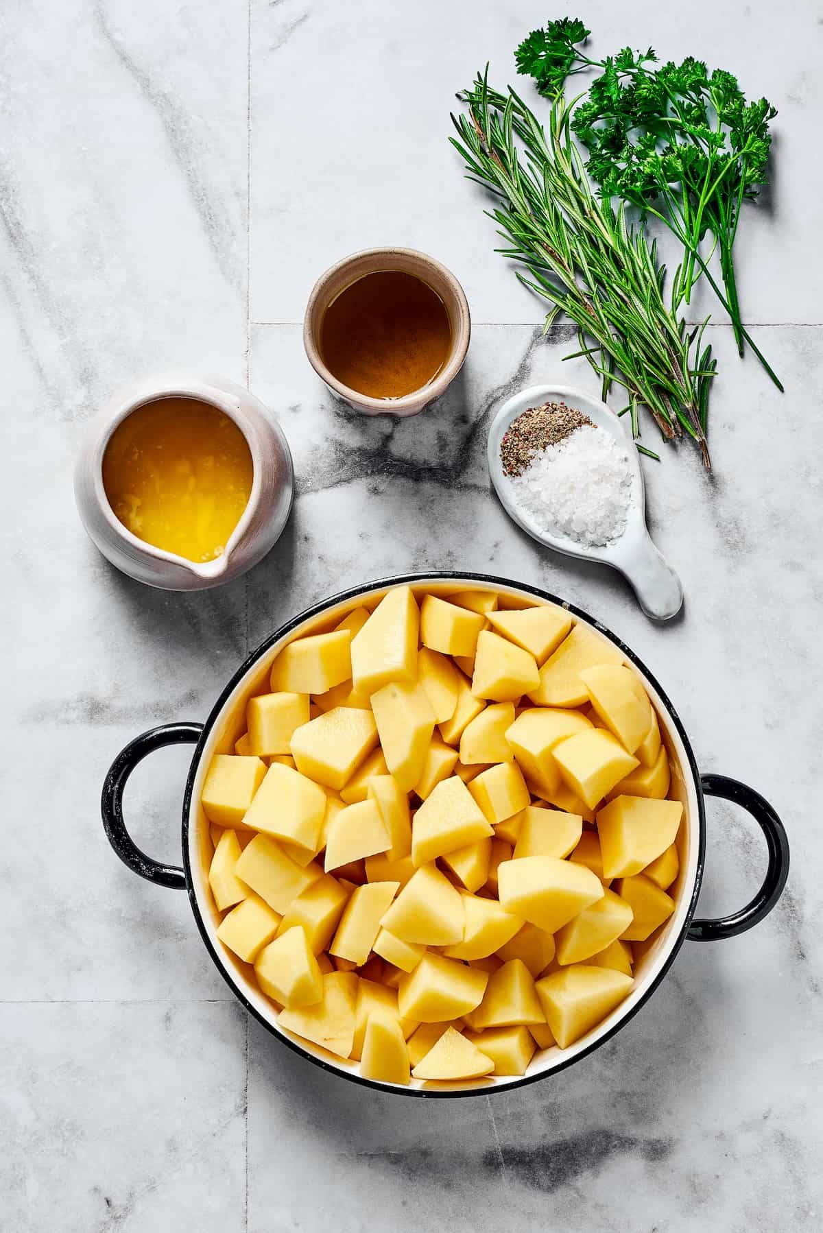 From top: Oil, fresh rosemary, fresh parsley, melted butter, salt and pepper, cut-up raw potatoes.