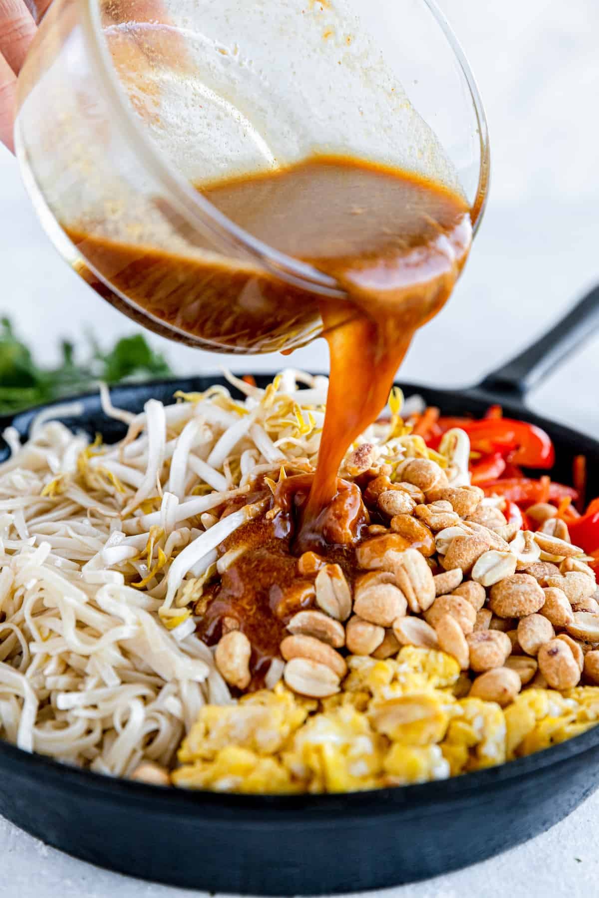 Pad Thai Sauce Being Poured Over the Skillet of Prepared Pad Thai