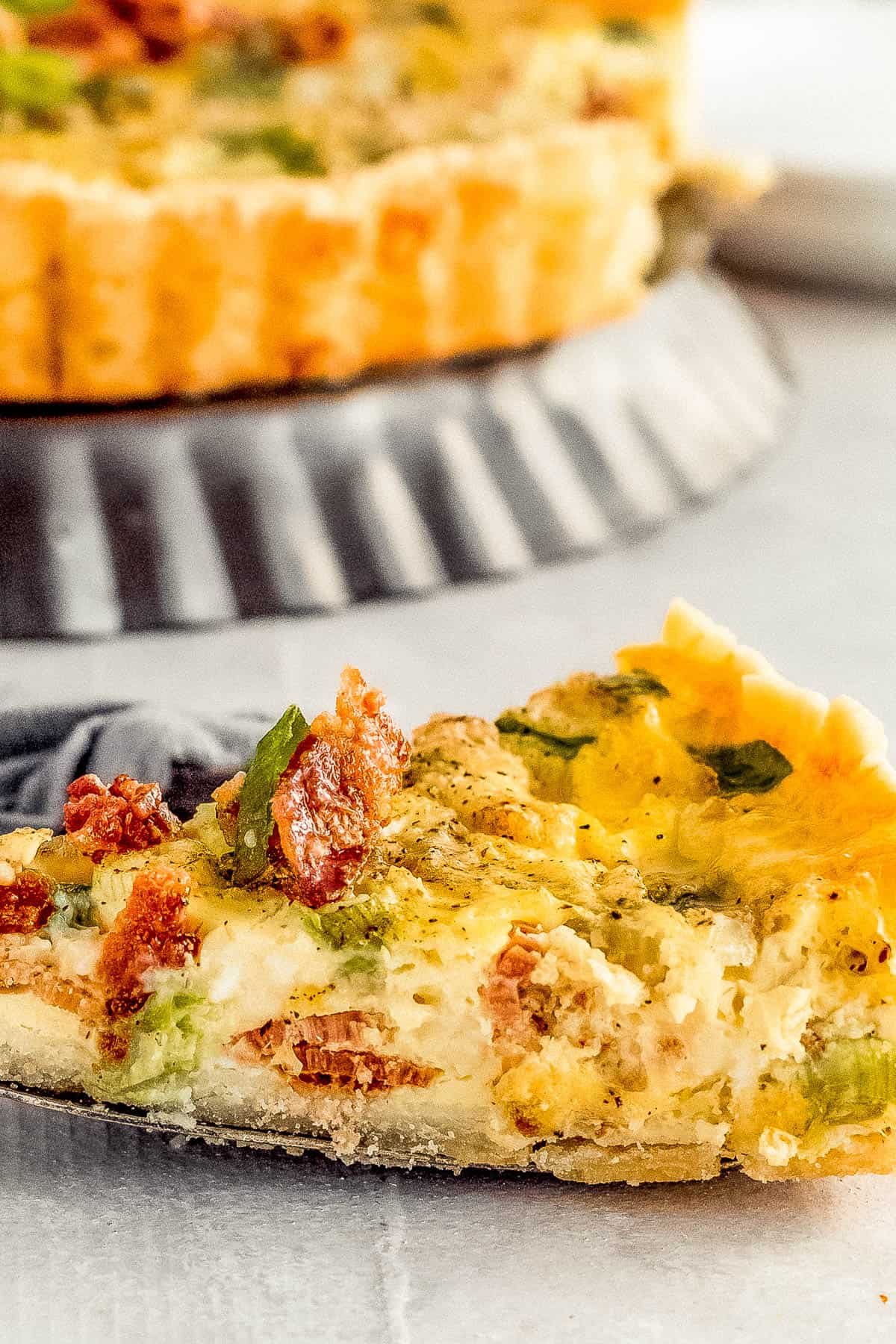 A Close-Up Shot of a Slice of Bacon Quiche Lorraine on a Metal Serving Spatula